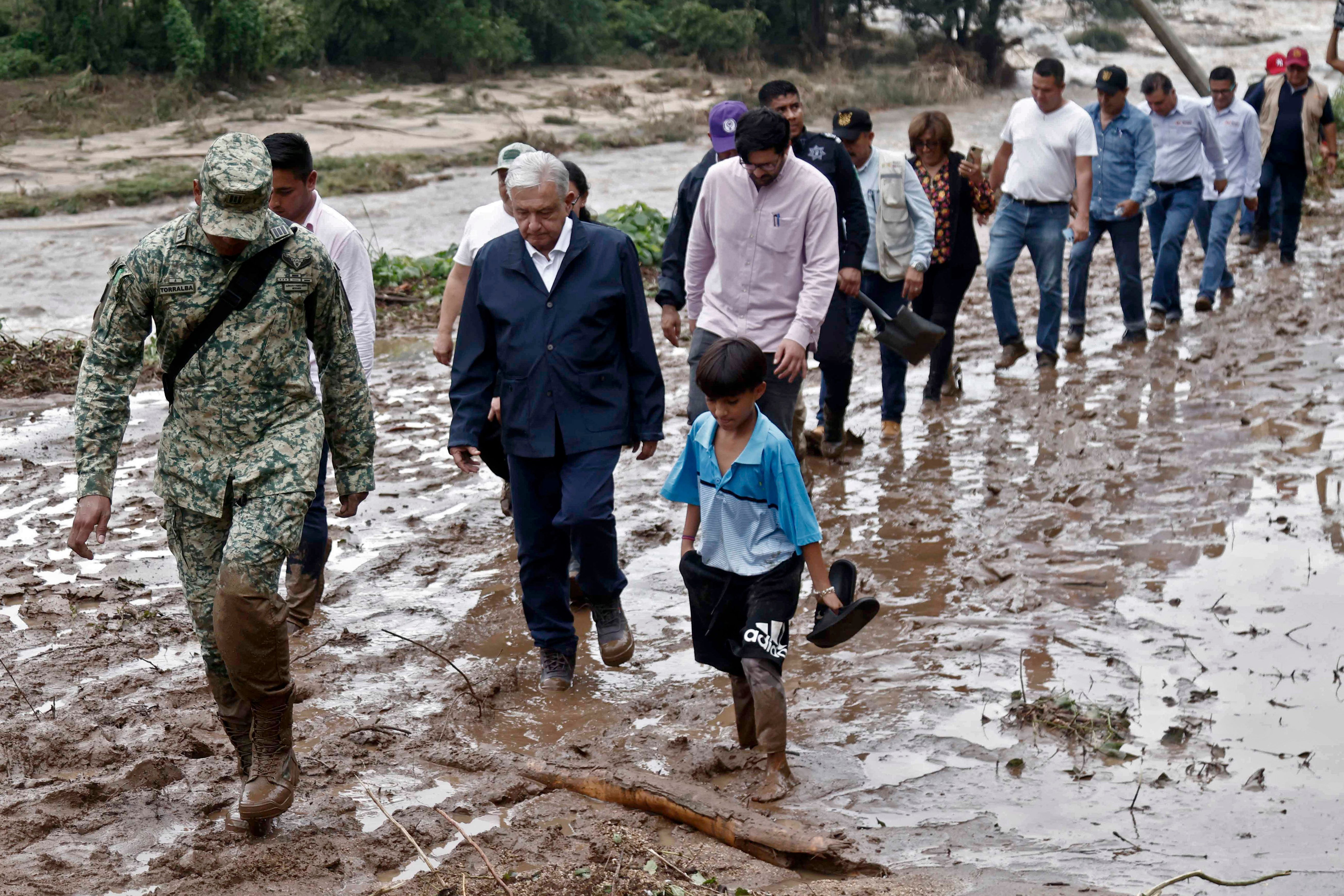 Mexican President Andres Manuel Lopez Obrador walking with residents, a soldier and members of his cabinet walk near Acapulco on Oct. 25.