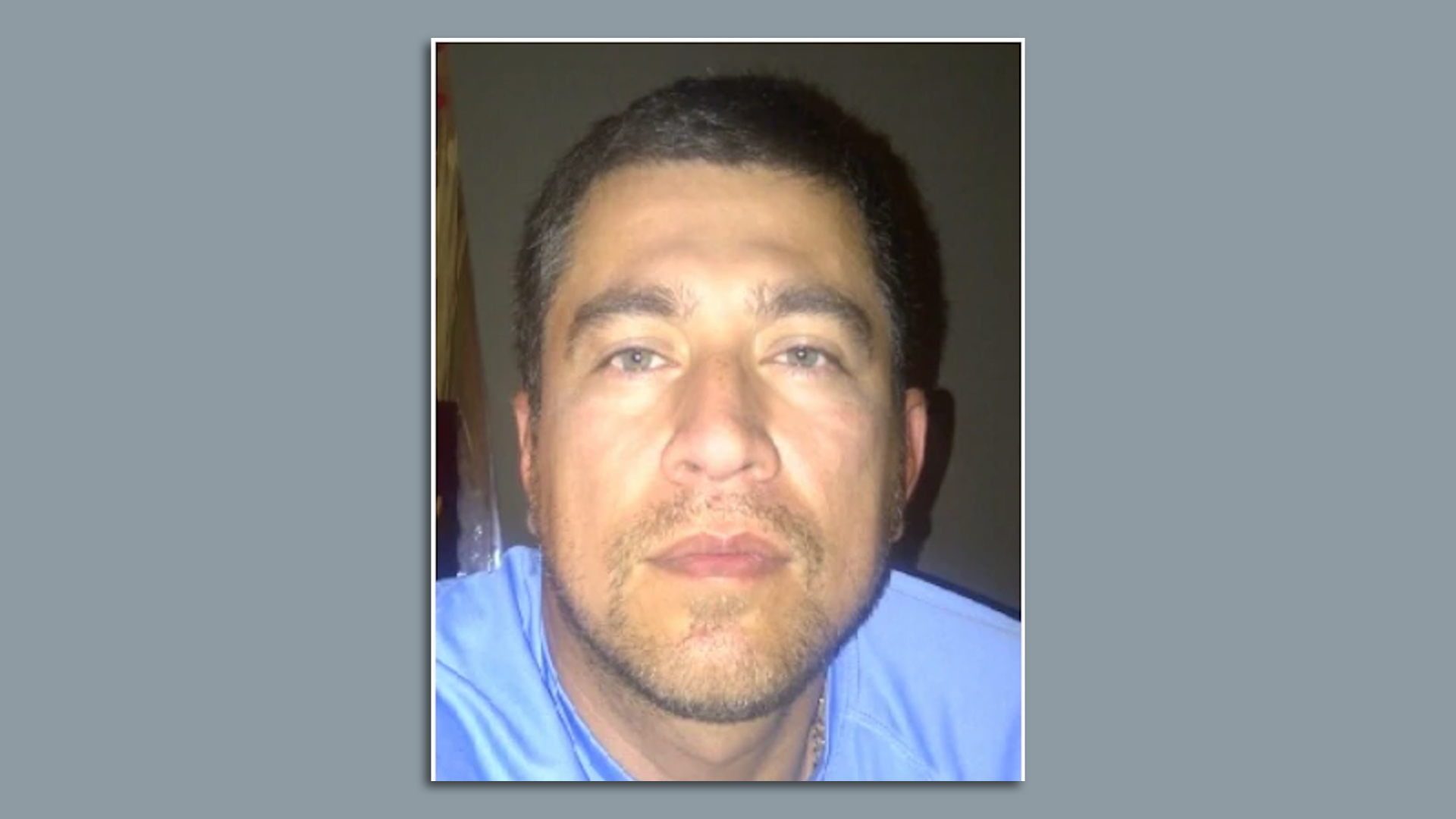 A man in a blue shirt looks at the camera