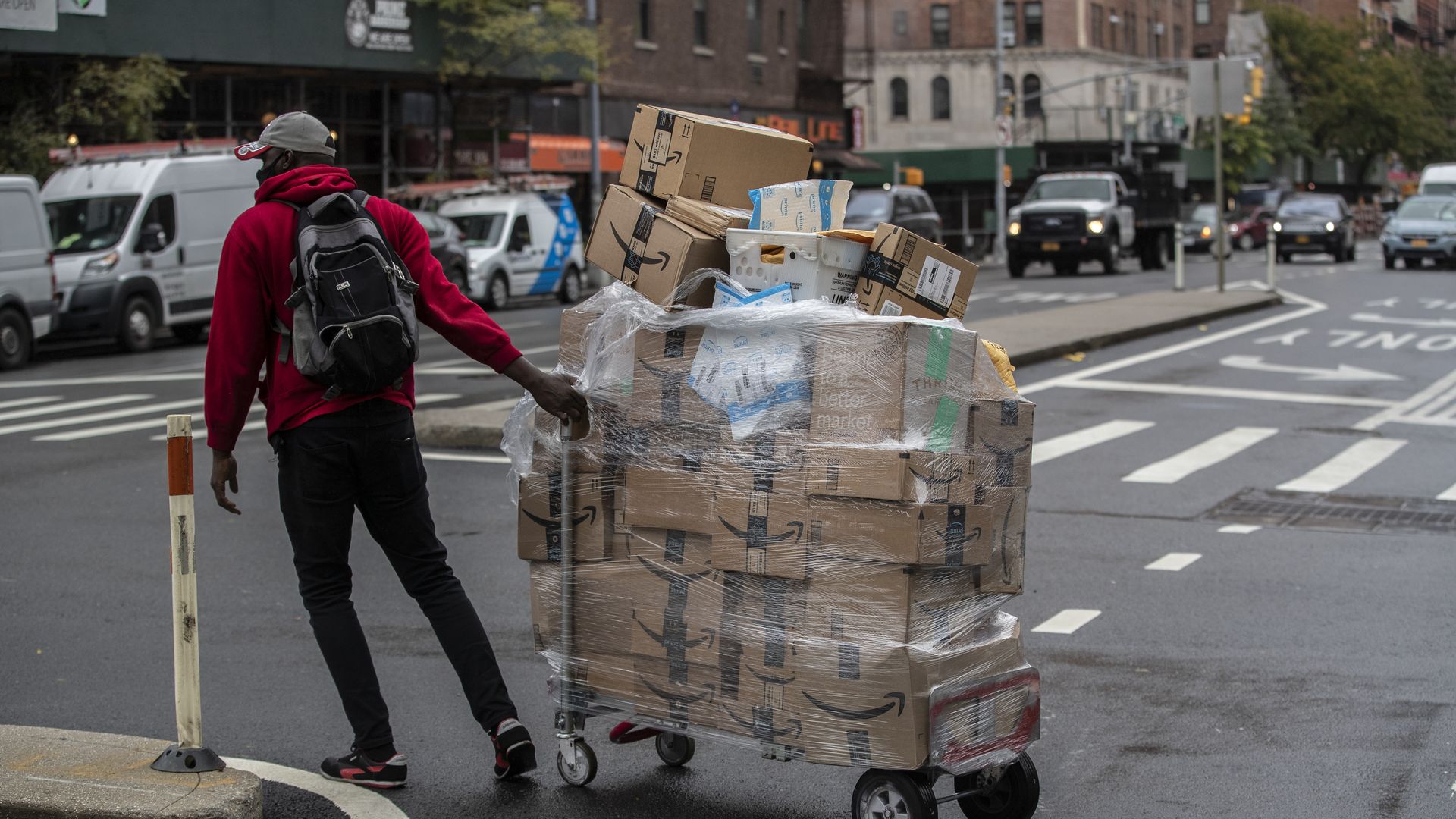 A worker wheels a cart of Amazon packages during a delivery in New York, U.S., on Tuesday, Oct. 13