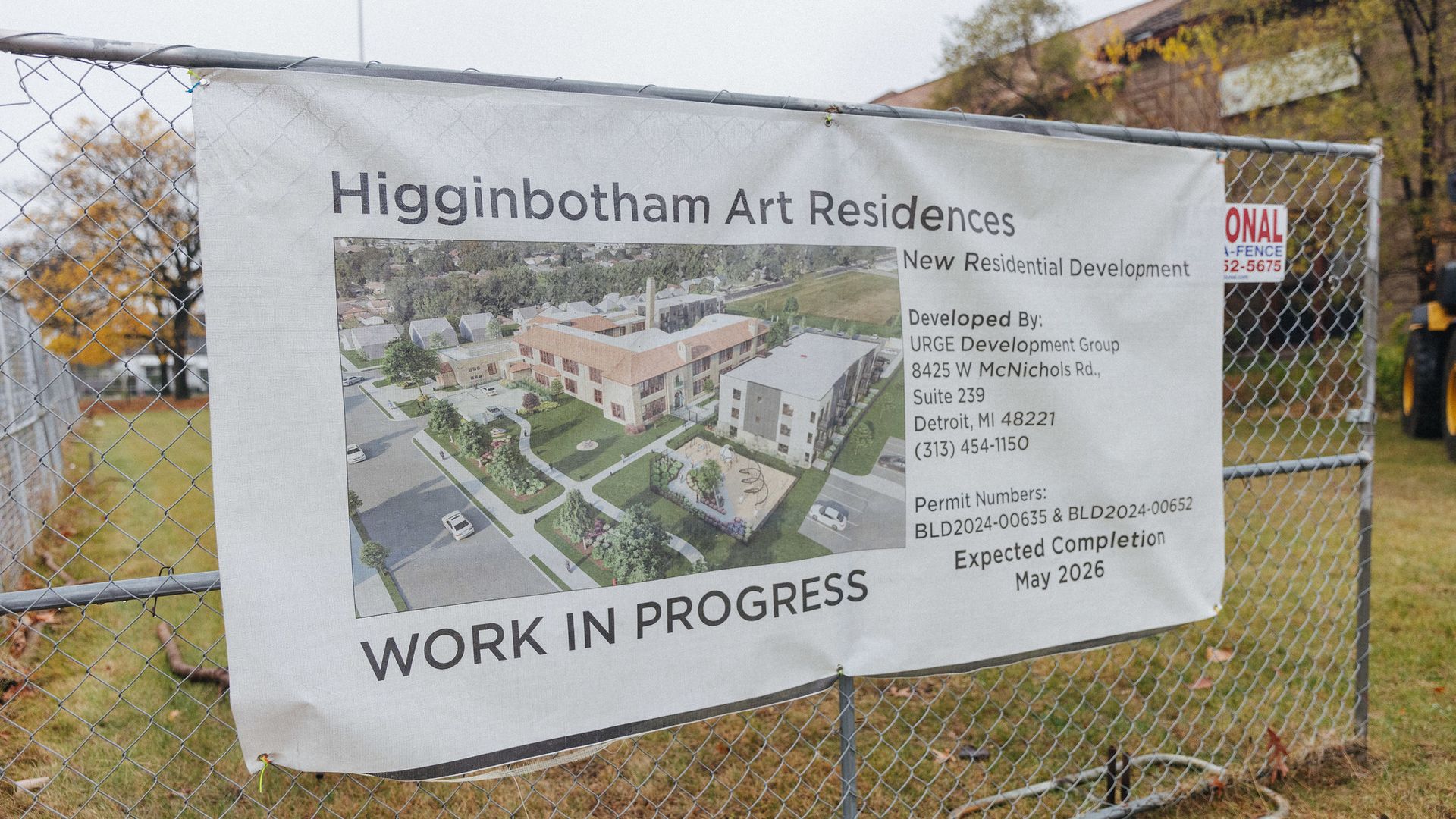 A banner outside the school building shows a rendering of the project. It says 