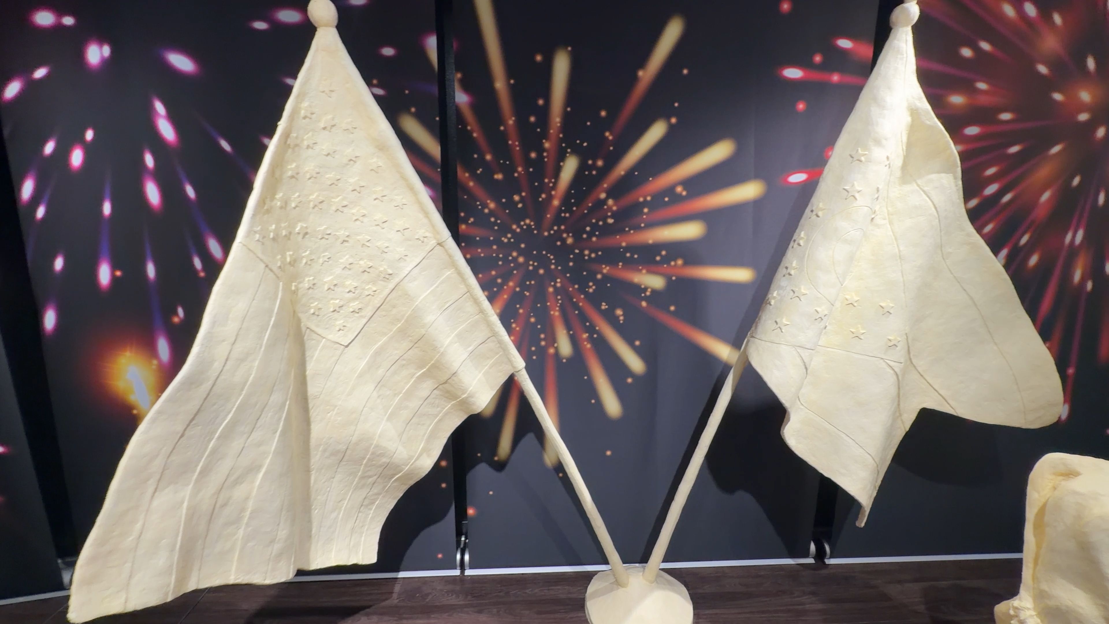 An American flag and an Ohio flag sculpted from butter, amid a backdrop of fireworks.