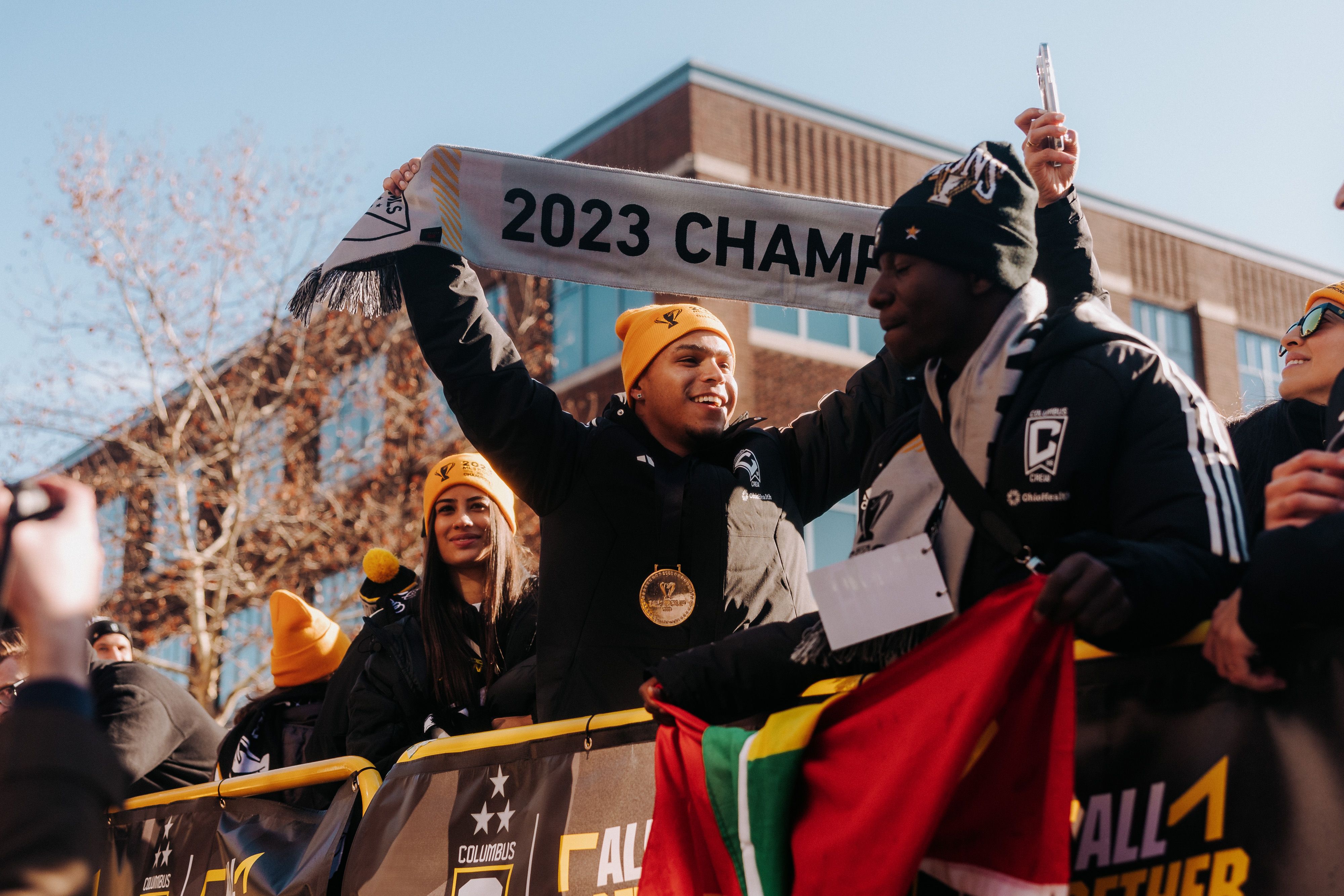 Cucho Hernandez holds a "2023 Champs" scarf on a parade float