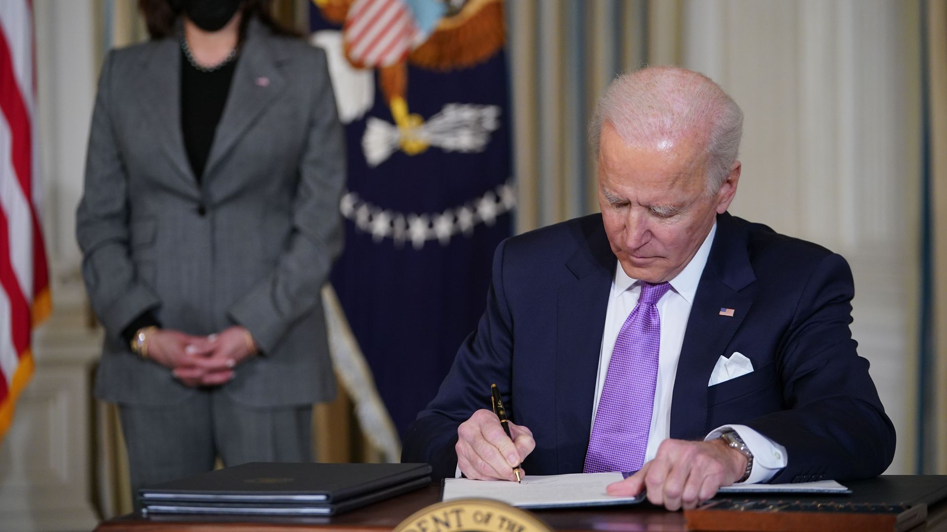Photo of Biden signing an order in the Oval Office