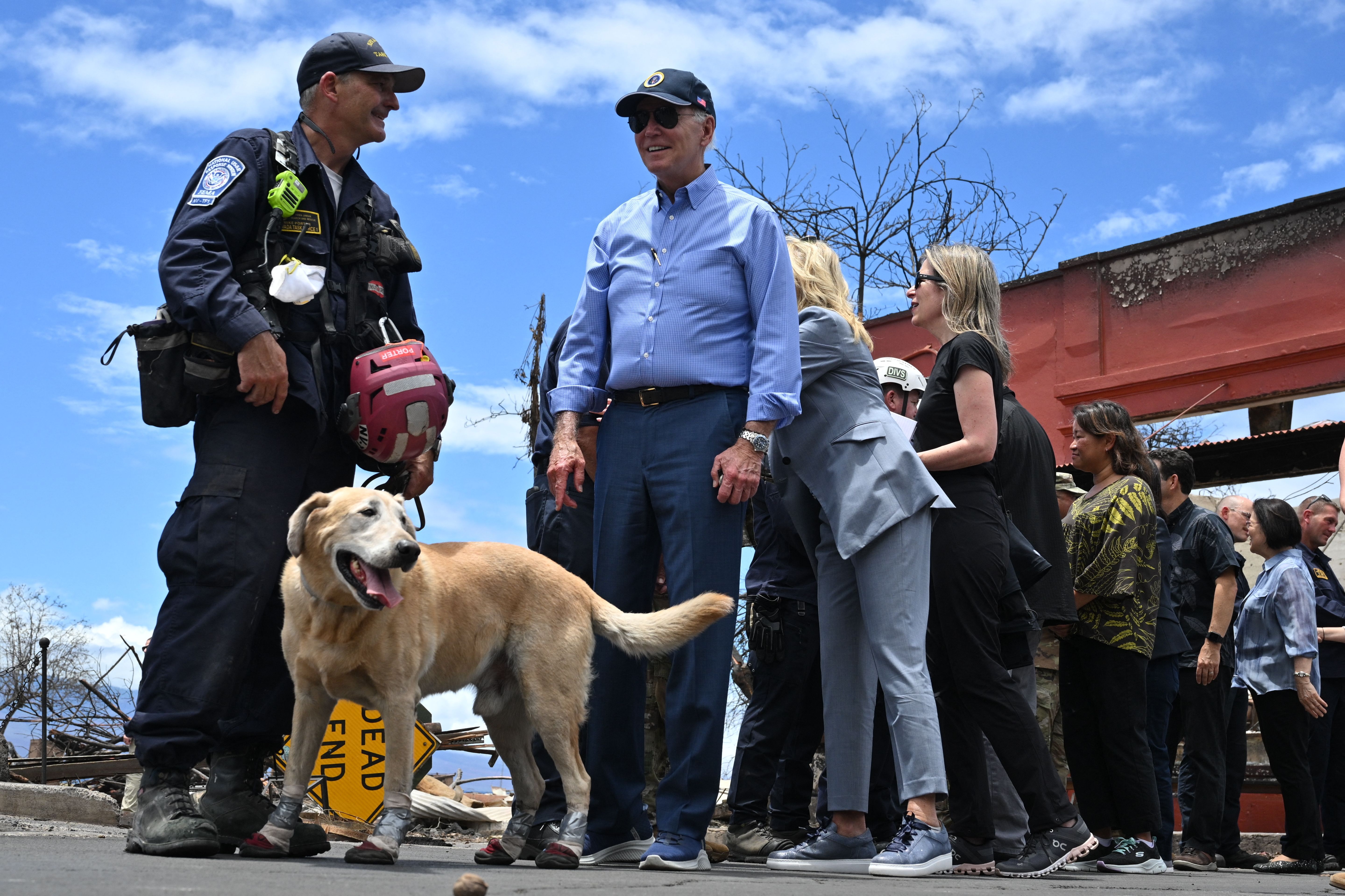 President Joe Biden (C) greets a rescue dog wearing protective boots as he meets with first responders during an operational briefing on response and recovery efforts following wildfires in Lahaina, Hawaii on August 21, 2023. The Bidens are expected to meet with first responders, survivors, and local officials following deadly wildfires in Maui.