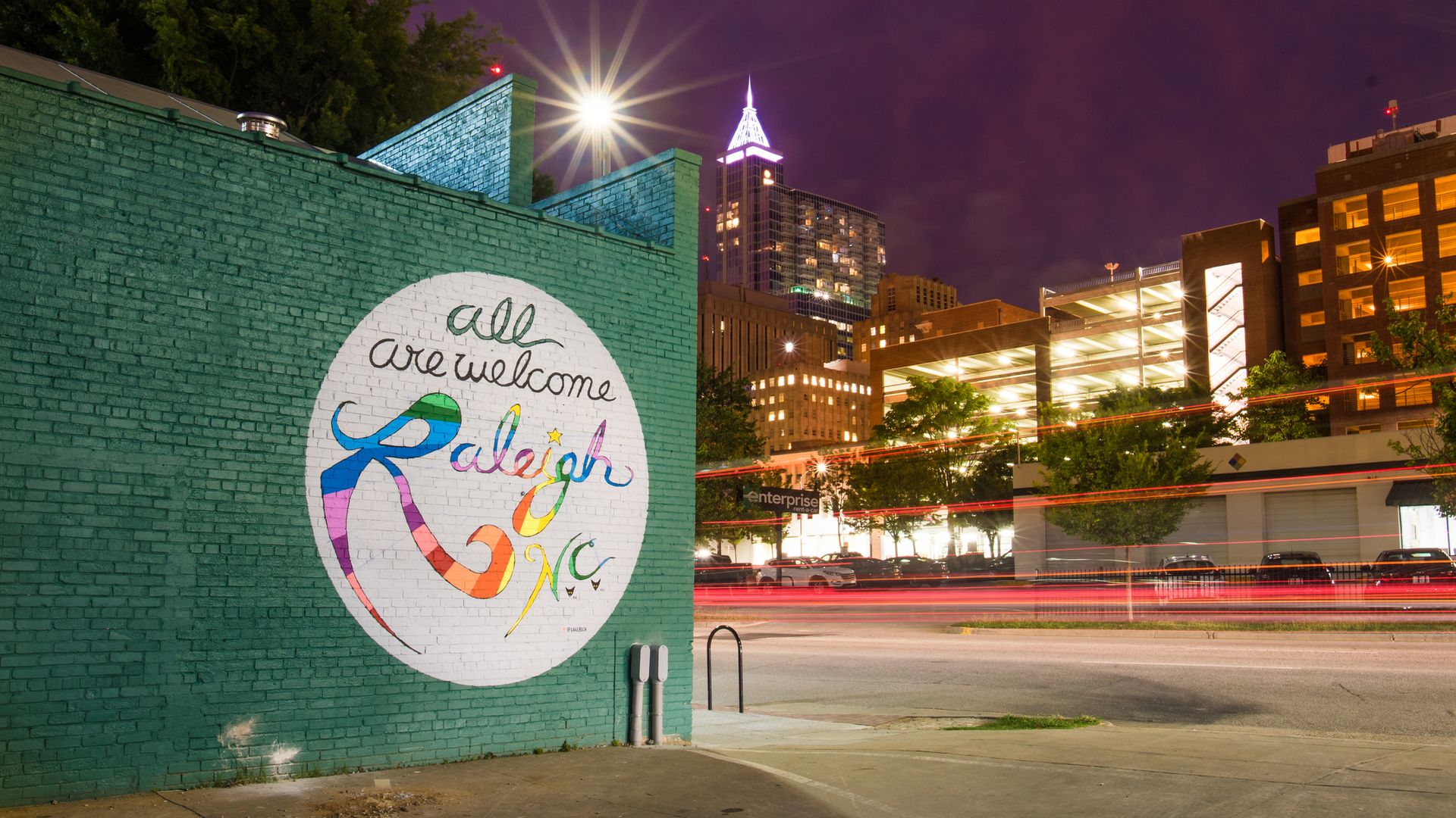 A mural that reads "all are welcome Raleigh N.C." 