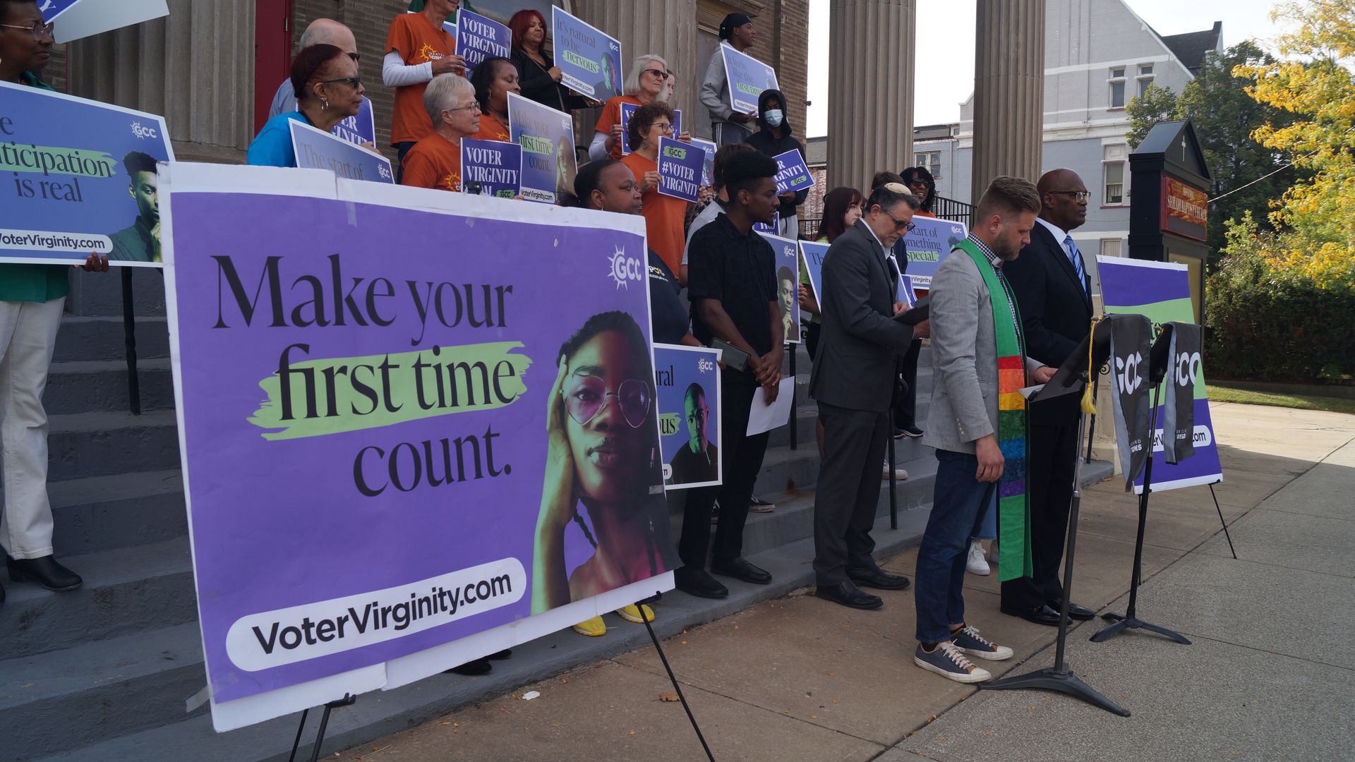 A sign reading "Make your first time count" next to people standing on steps of a church