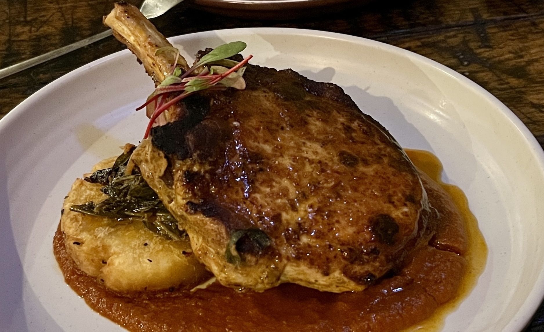 Two pork chops with a brown sauce on a white plate.