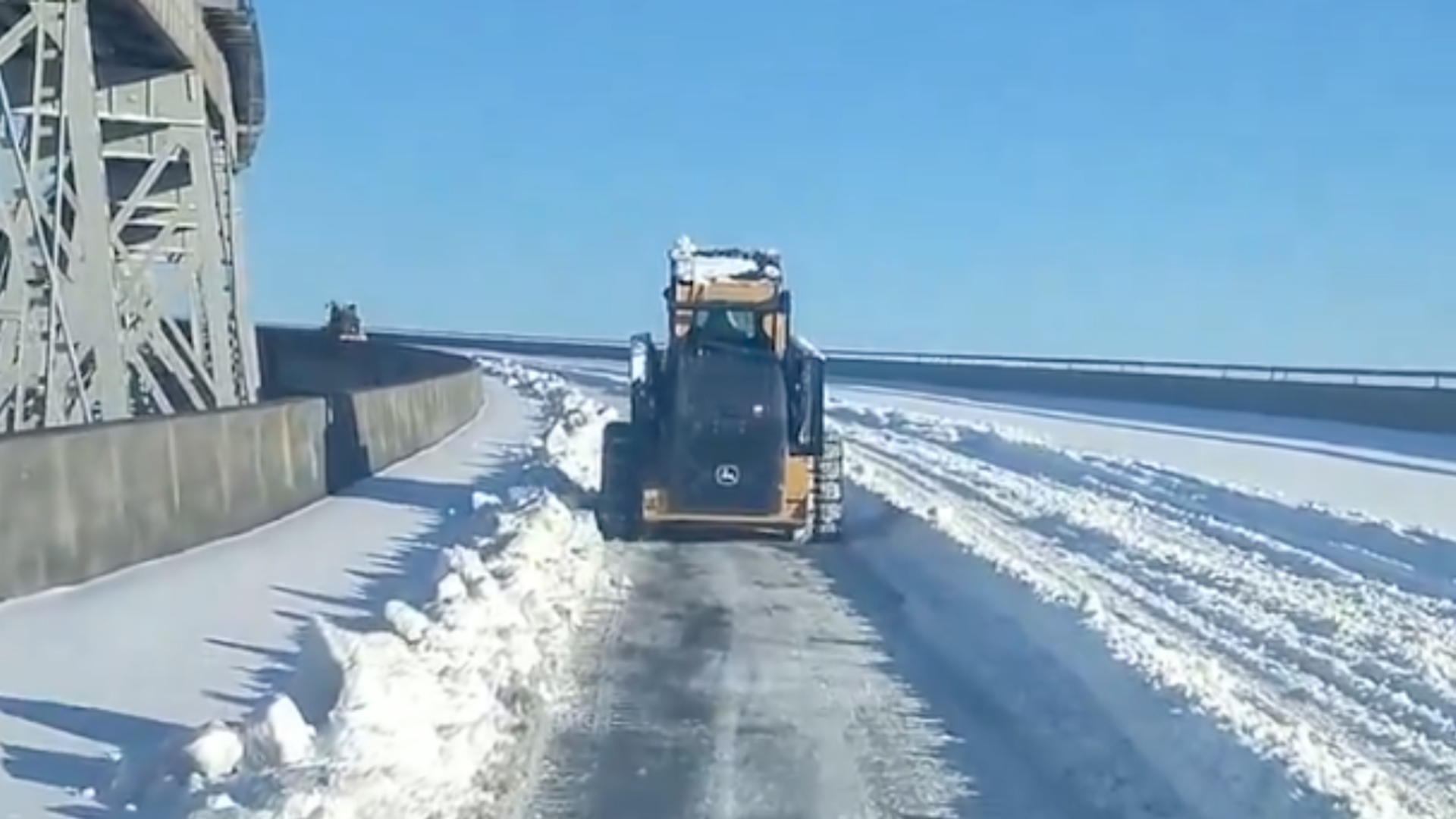 Photo shows a truck plowing a bridge.