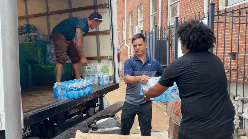 a video showing a human assembly line, with people getting cases of water out from a truck