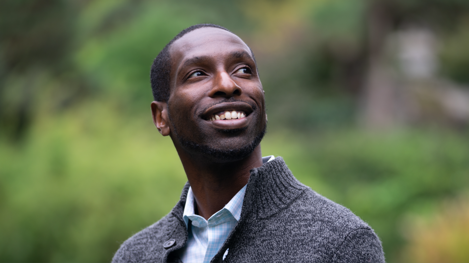Marcus Harrison Green, the founder of the South Seattle Emerald and head of Hinton Publishing, looks up over his shoulder with greenery in the background. 