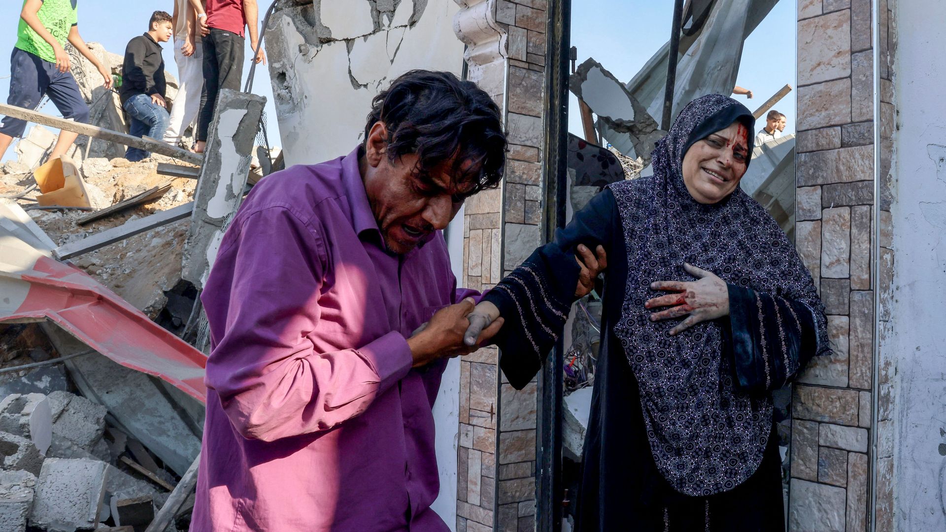Palestinians look for survivors in the rubble of a destroyed building hit during an Israeli air strike as an injured woman is helped in Rafah in the southern Gaza Strip, on October 13, 