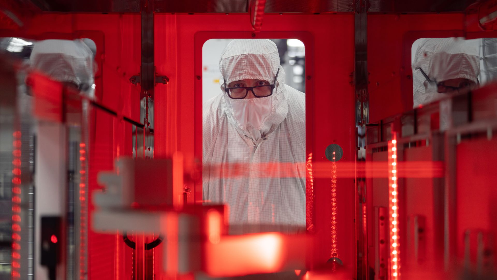 a worker peers into a lab through a window.