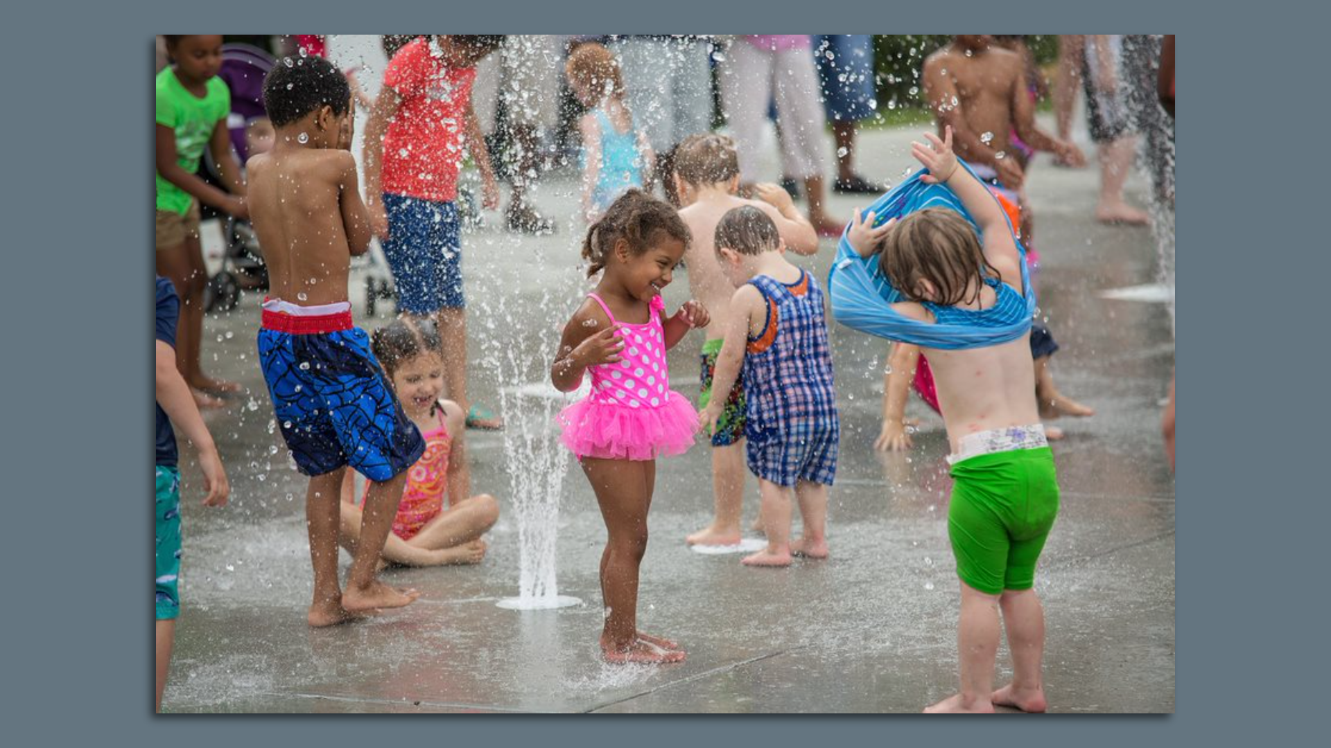 A bunch of small kids stand in a splash pad