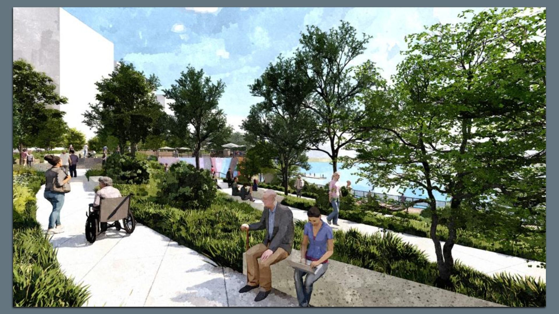 Urban waterfront park with trees, shrubs, and paved paths. People walk and sit; a person in a wheelchair, with water and buildings in the background.