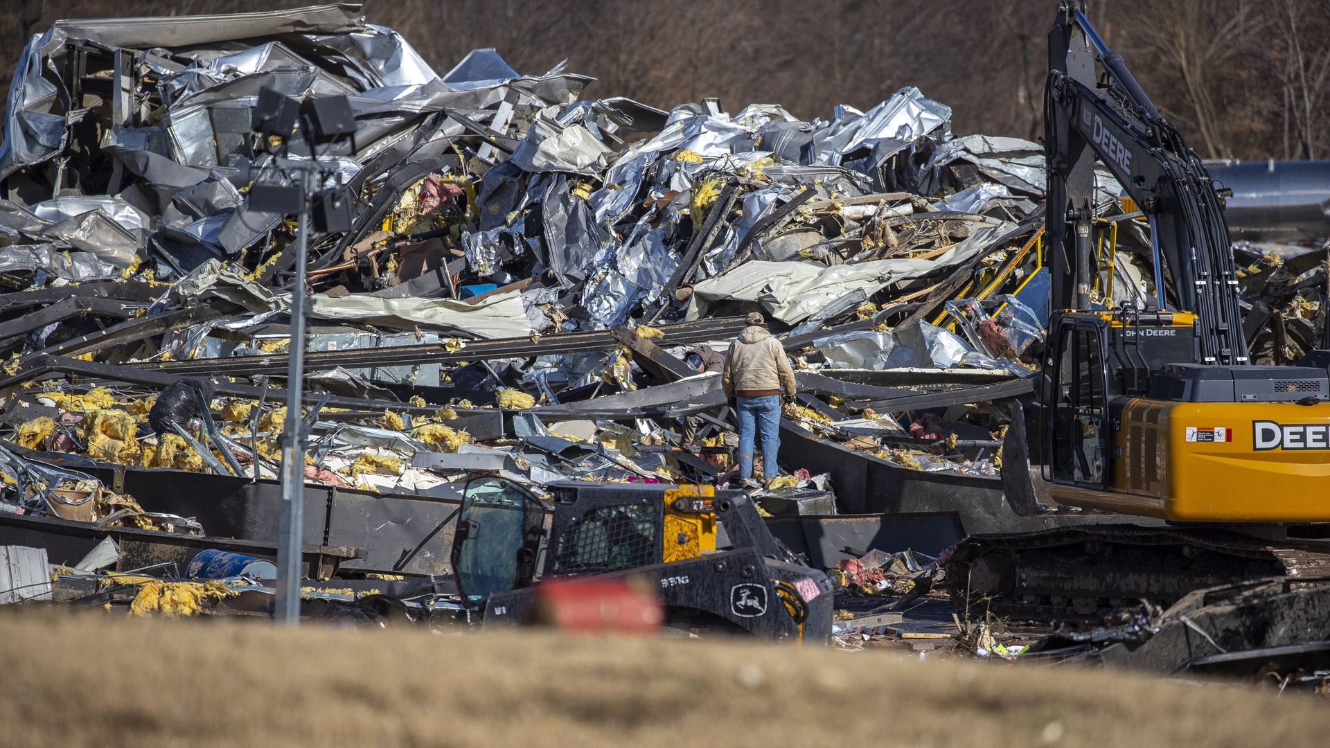 Photo of a person standing on crushed rubble surveying the damage to what was once a factory