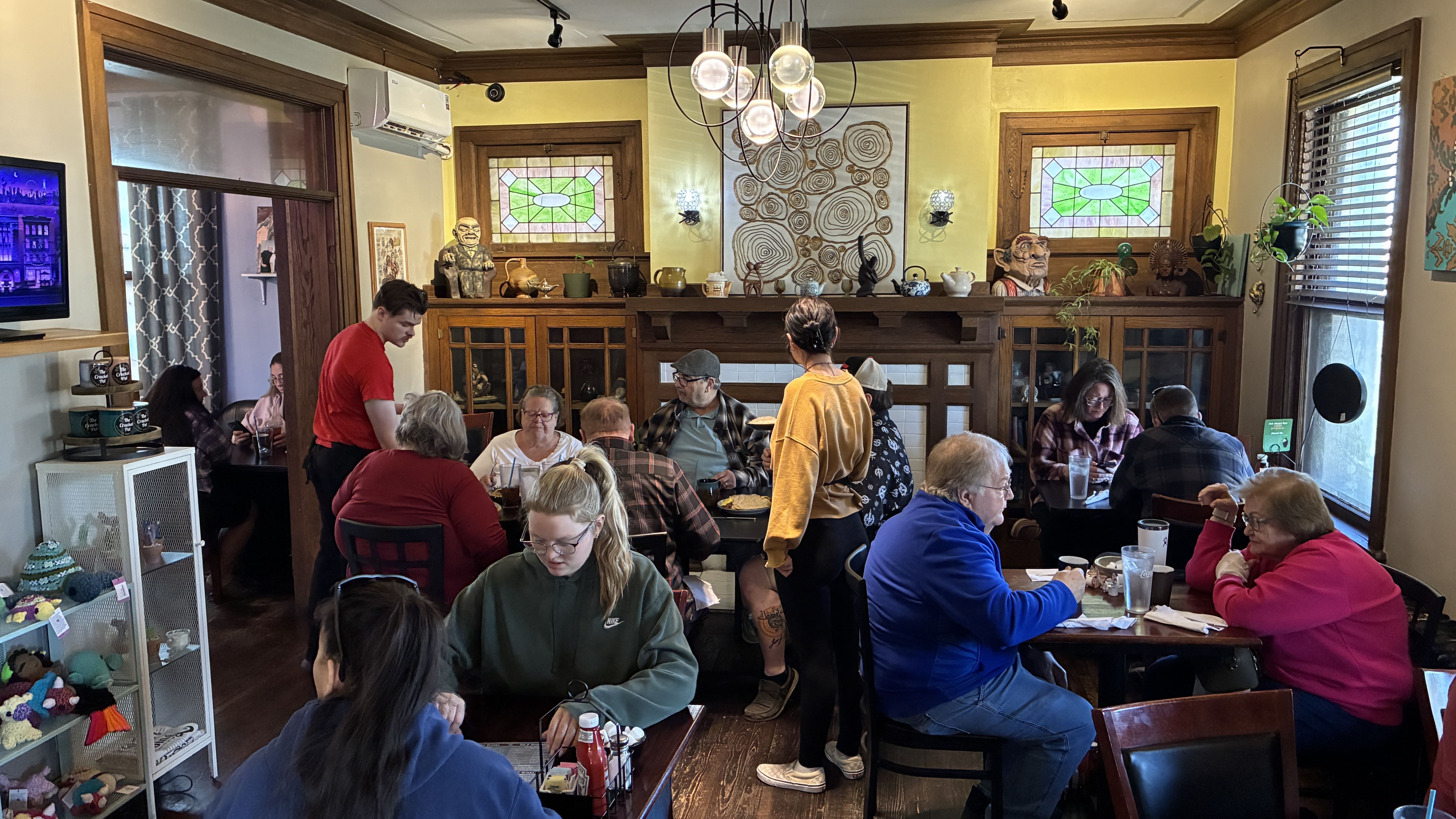 Every table is full inside the main dining room at The Cracked Pot. Servers attend to two of the tables.