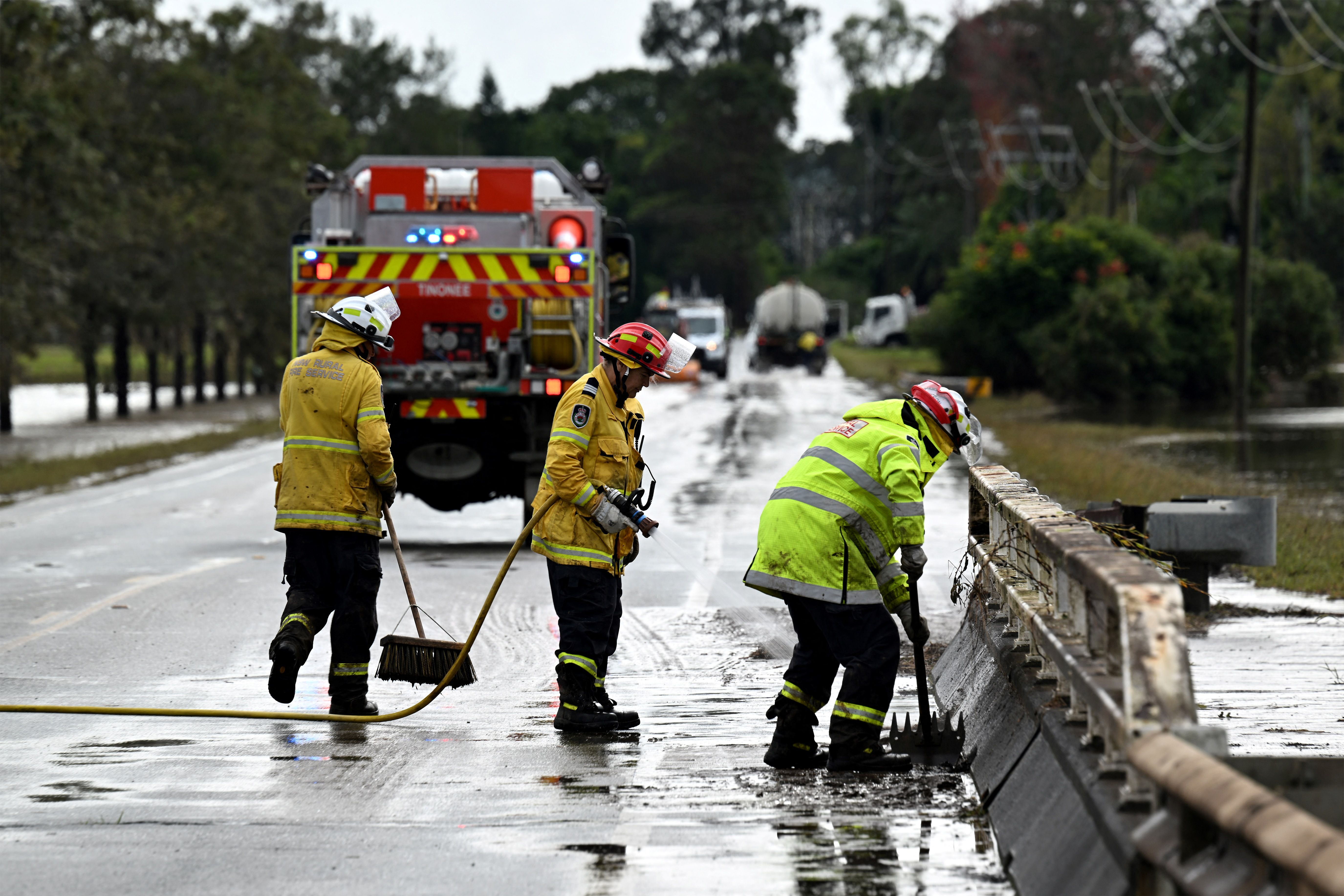 Fire Brigade officials clear silt as floodwaters recede from the main road in Taree on May 23, 2025. Record floods cut a destructive path through eastern Australia on May 23, caking houses in silt, washing out roads and separating 50,000 people from help. 