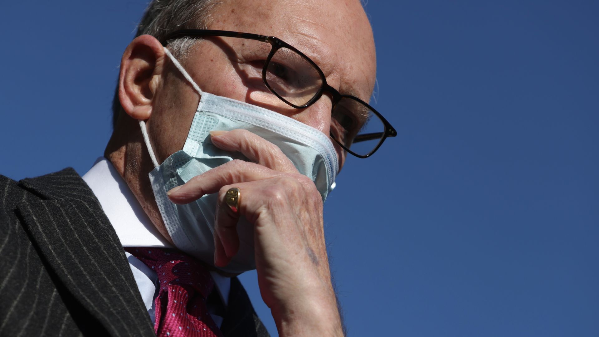 Photo of a masked Larry Kudlow holding a hand to his face