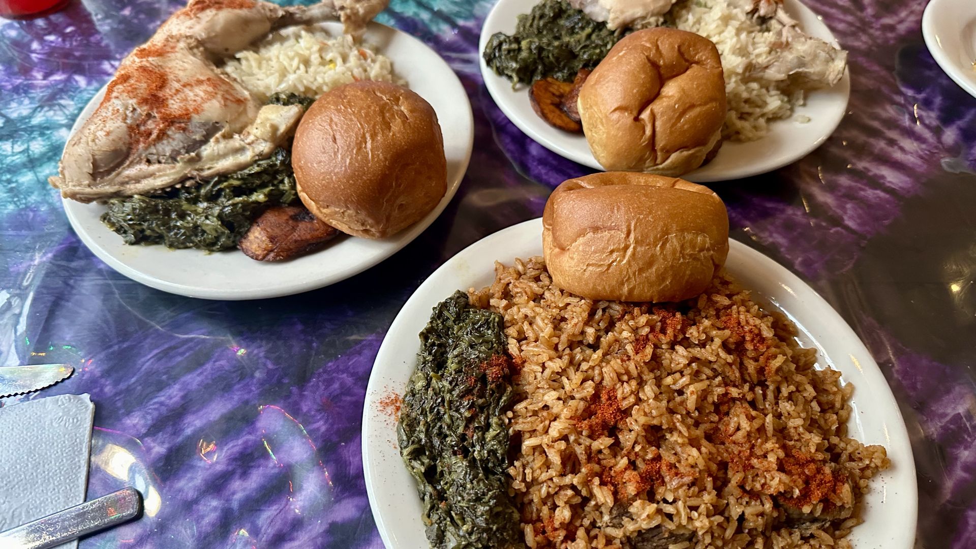 Photo shows three plates of food with rice, spinach and rolls.