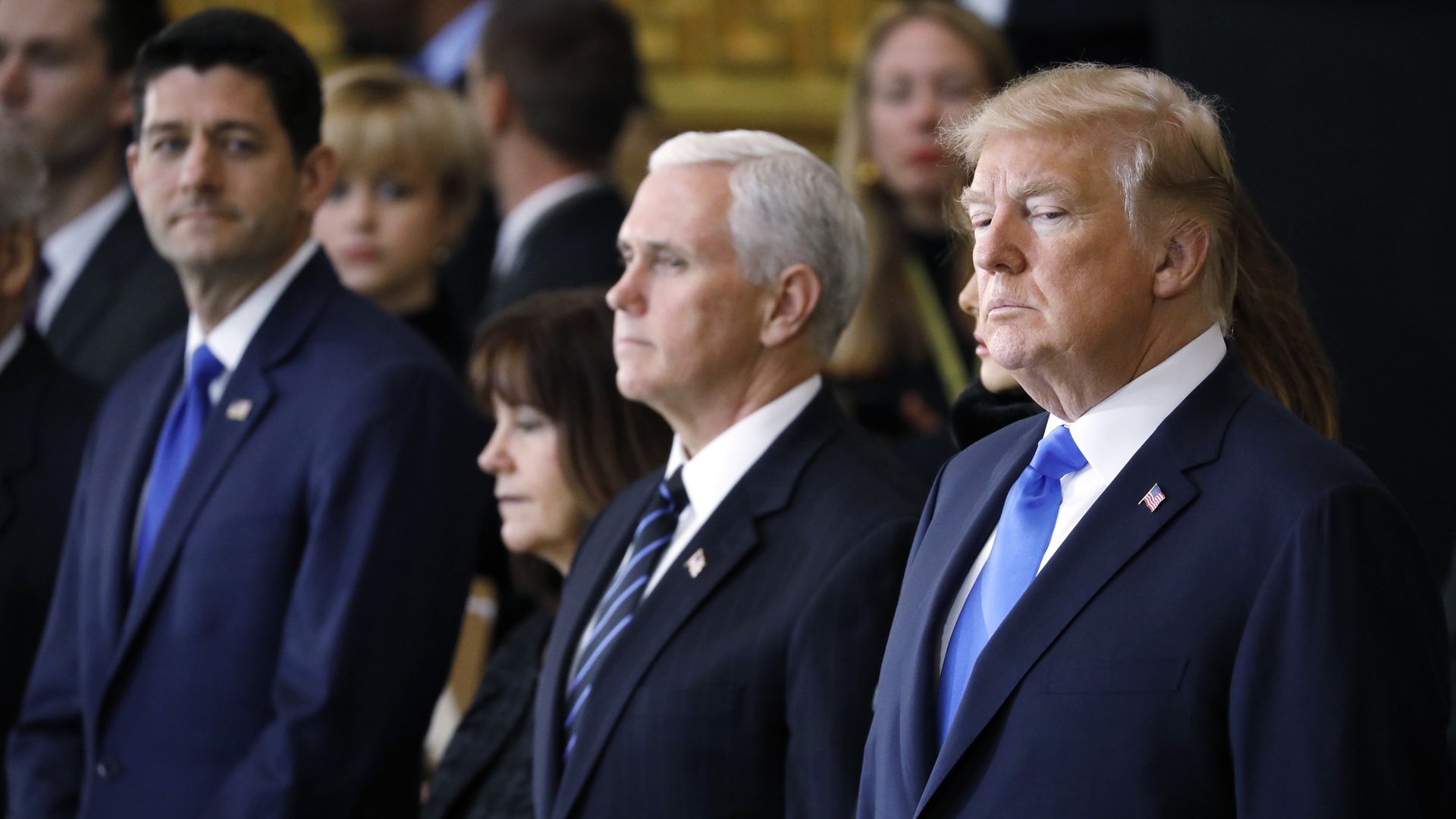 Paul Ryan looking over at Mike Pence and Donald Trump, who is looking down.