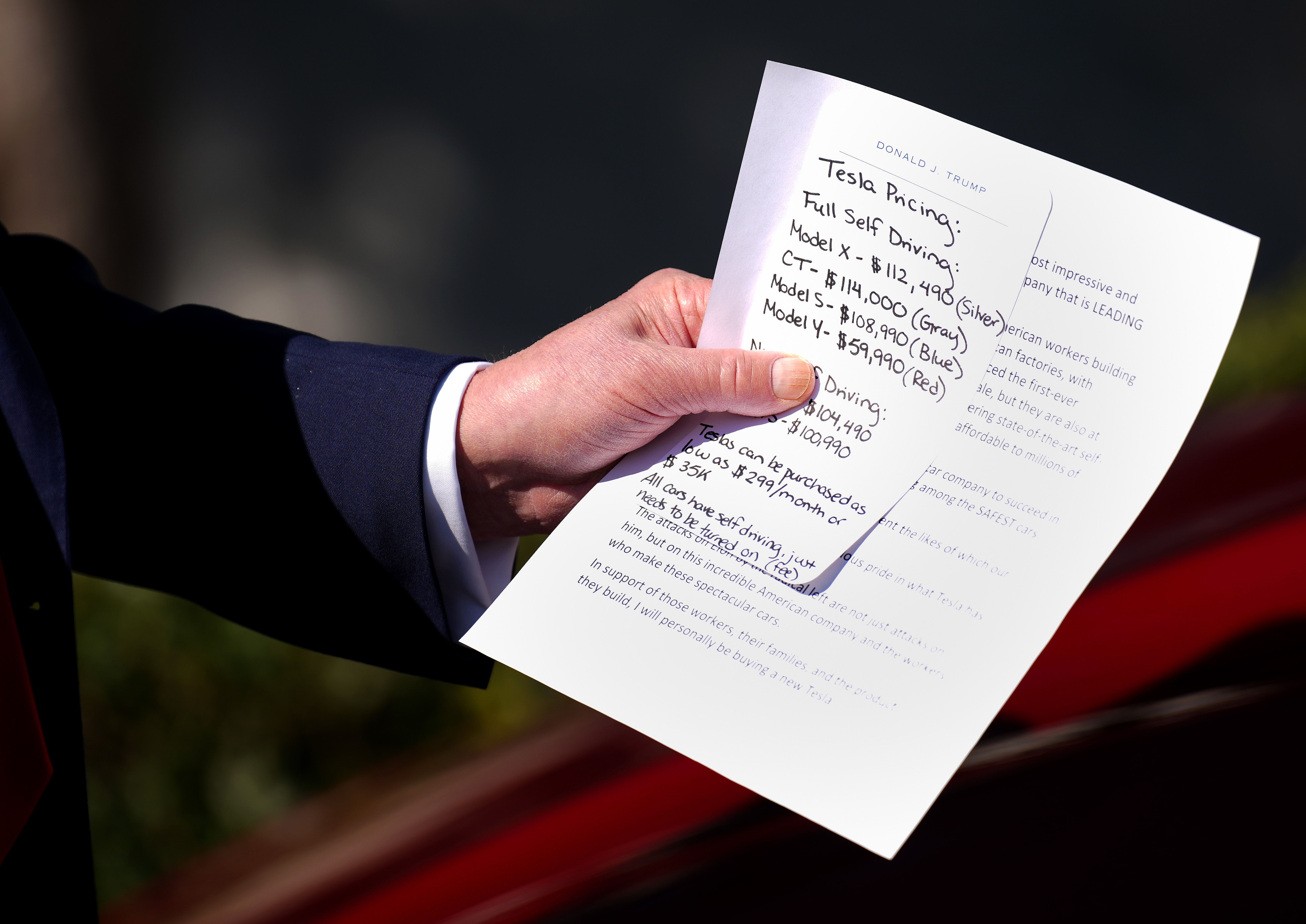 President Trump holds up notes on Tesla's models.