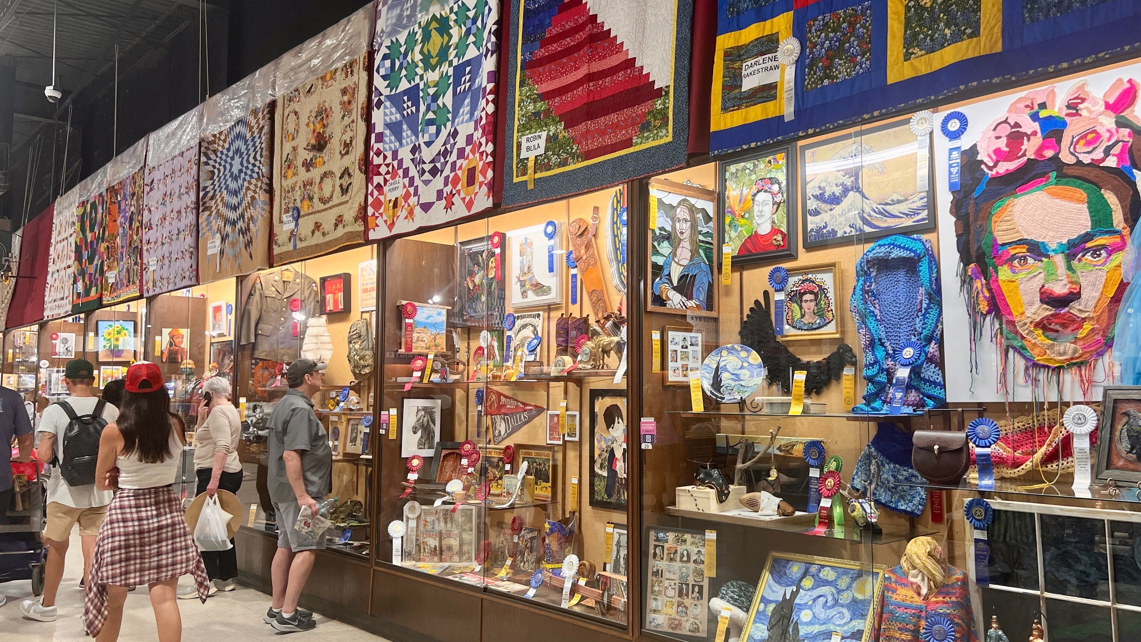 Displays of arts and crafts with people looking at them