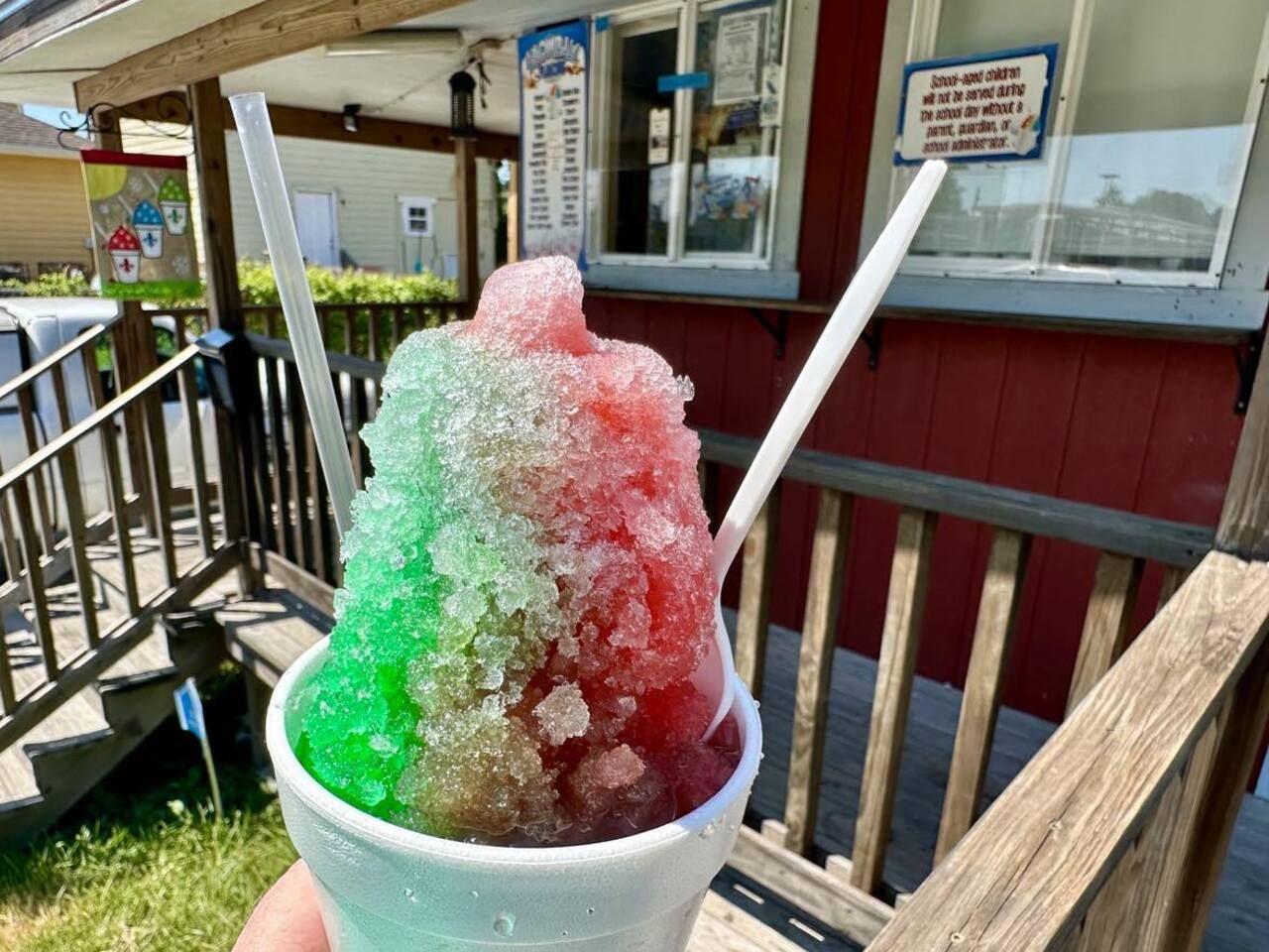 Photo shows a green and pink snoball in front of a wooden stand