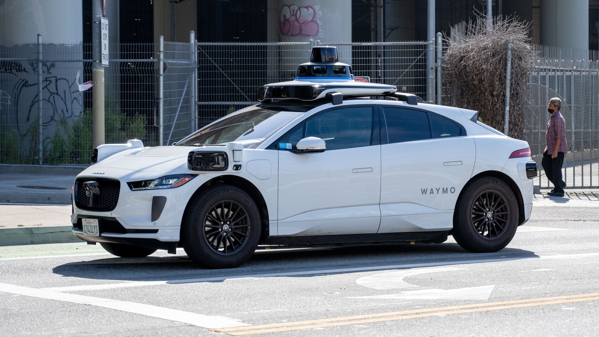 A white vehicle equipped with external sensors on an urban street