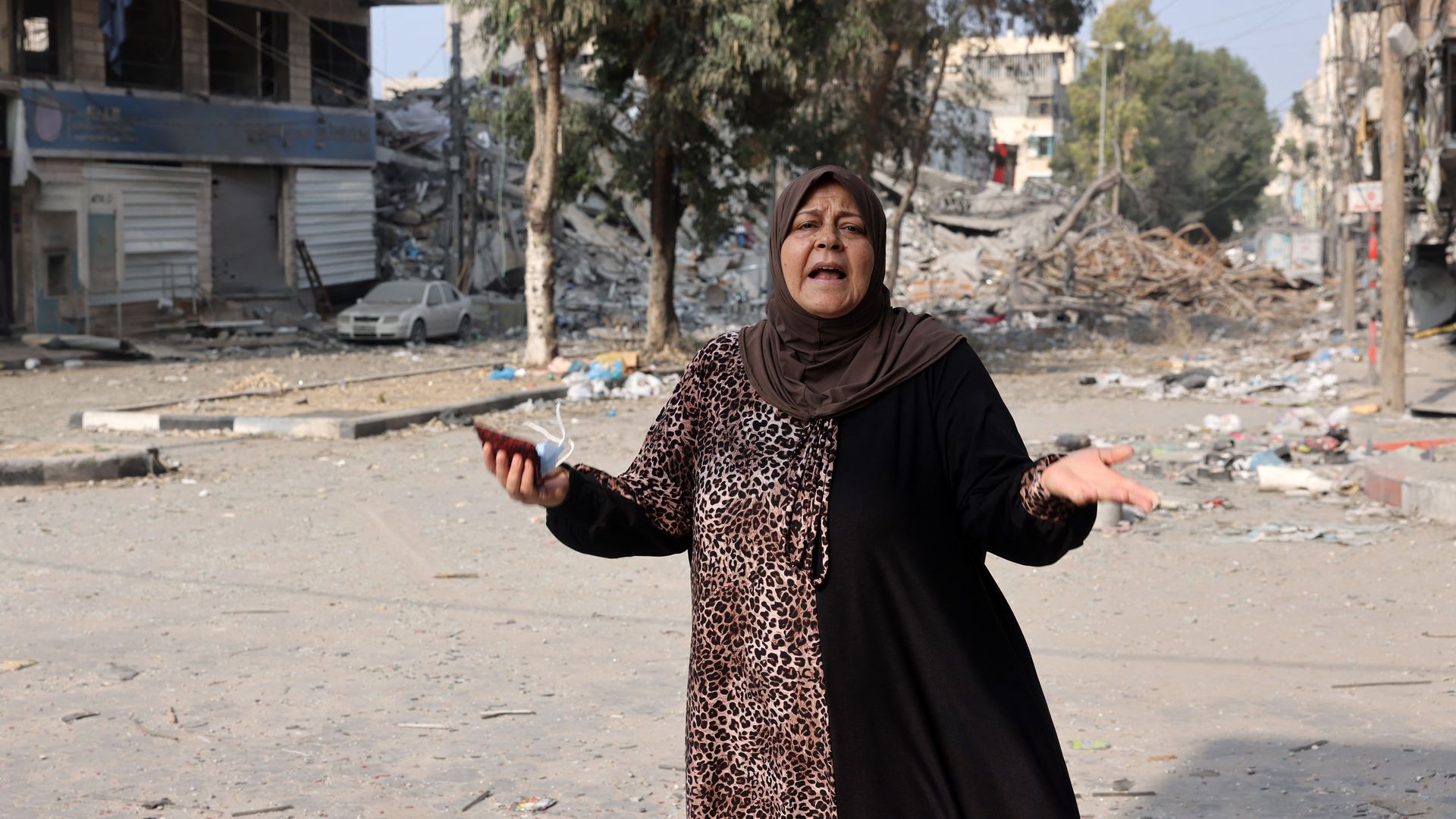 A woman reacts as she stands in front of buildings damaged in Israeli strikes in Gaza City