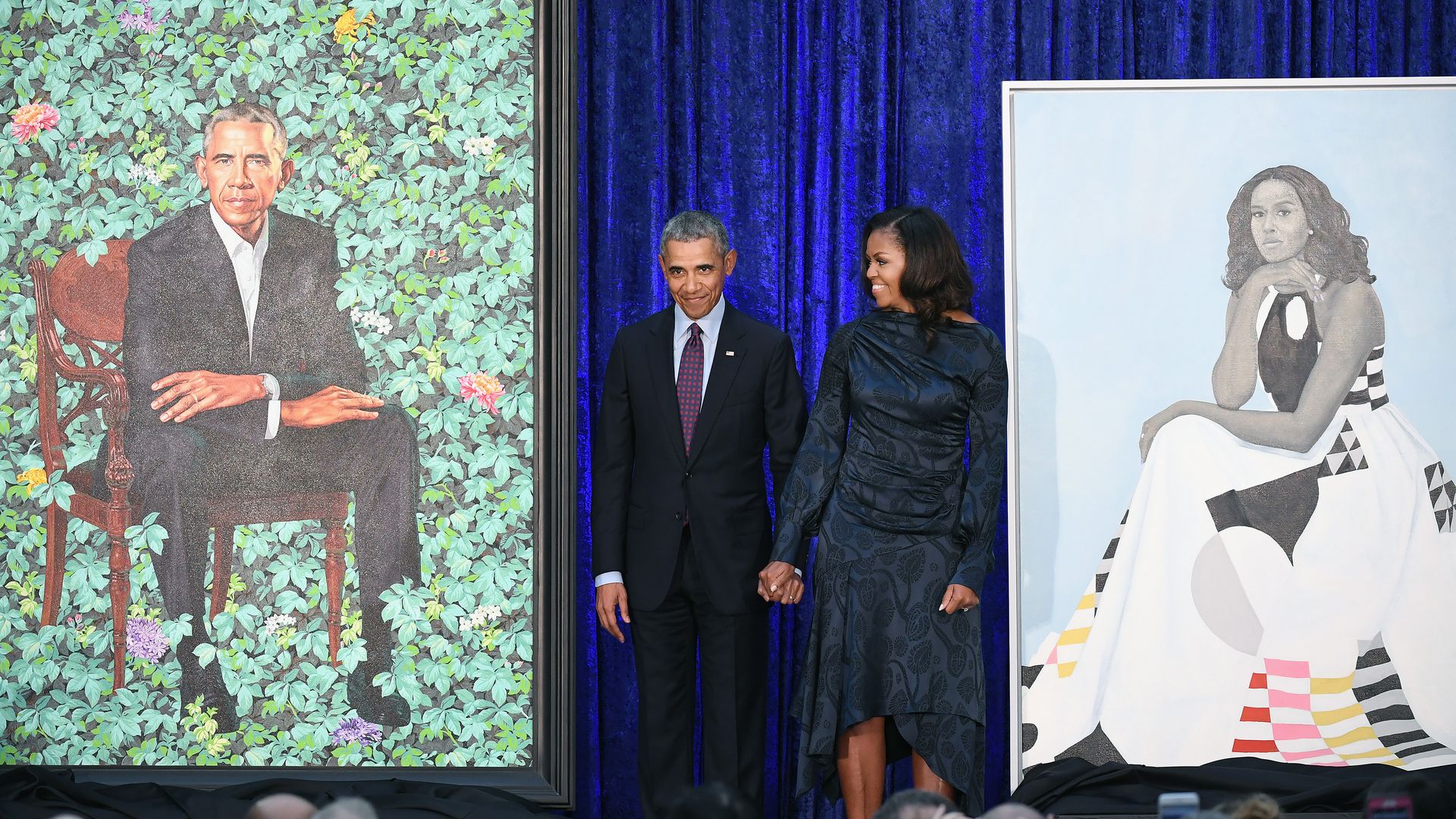 Former President Barack Obama and Michelle Obama next to their portraits