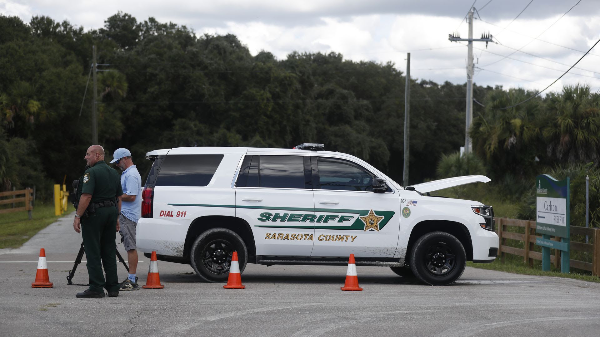 A Sarasota county sheriff stands next to his car by the T. Mabry Carlton Jr. Memorial Reserve.