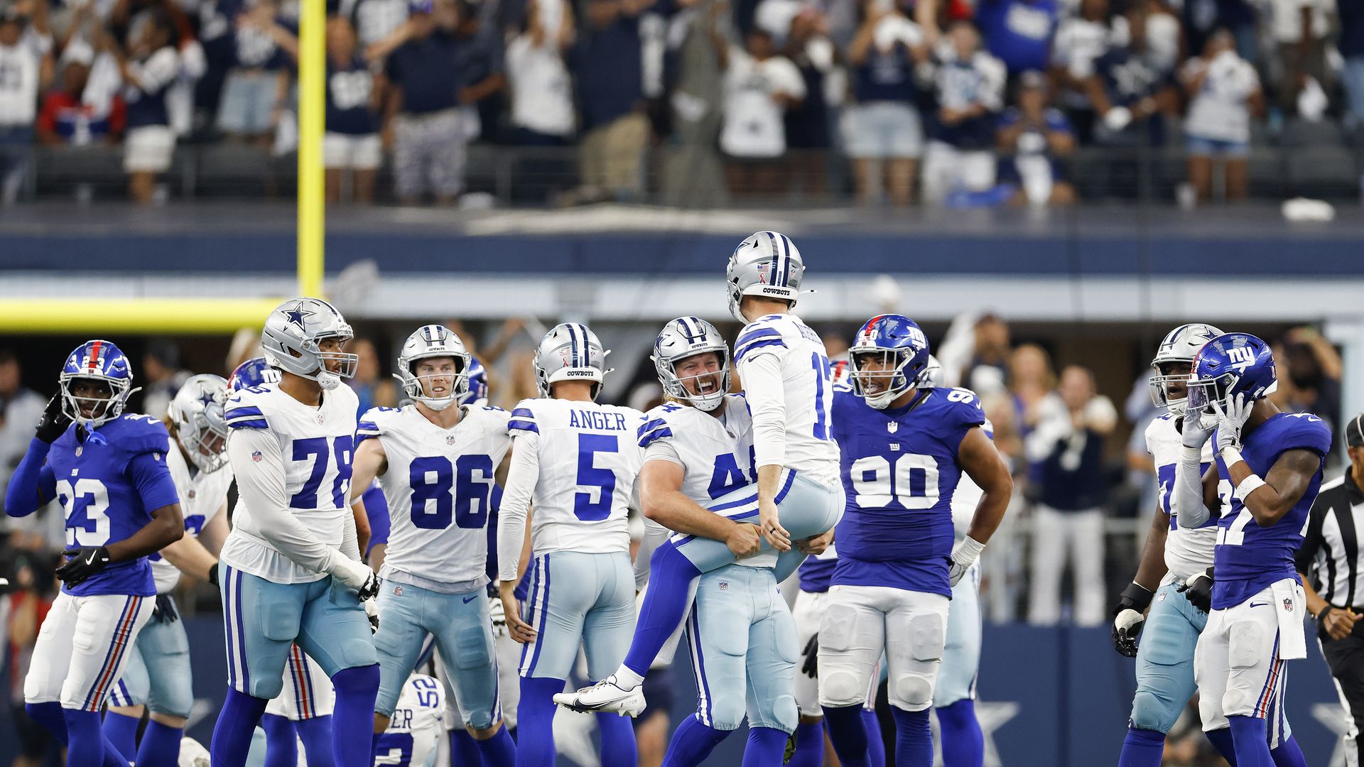 Trent Sieg lifts Brandon Aubrey in front of their Dallas Cowboys teammates with the field goal in the background at AT&T Stadium. 