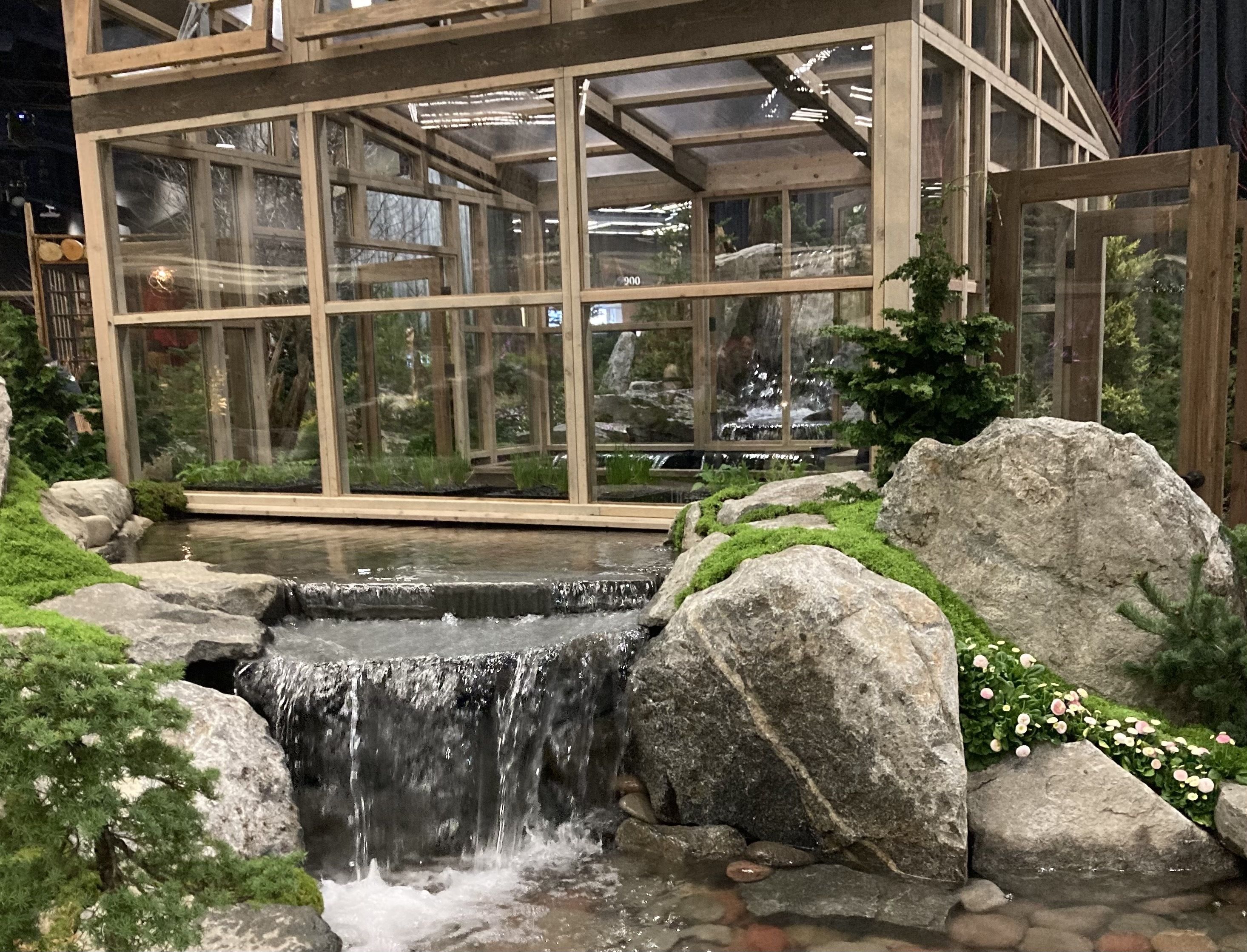 A greenhouse next to a small waterfall.