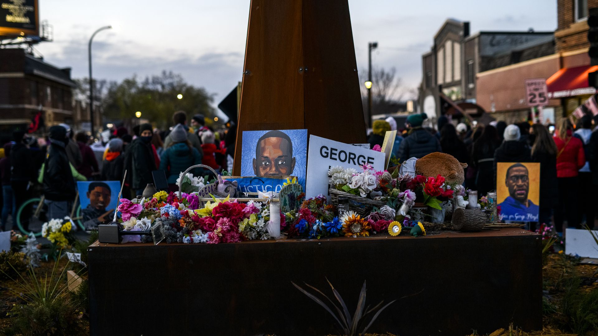 Photo of George Floyd Square, with signs and flowers sitting on the ground in memorial of Floyd