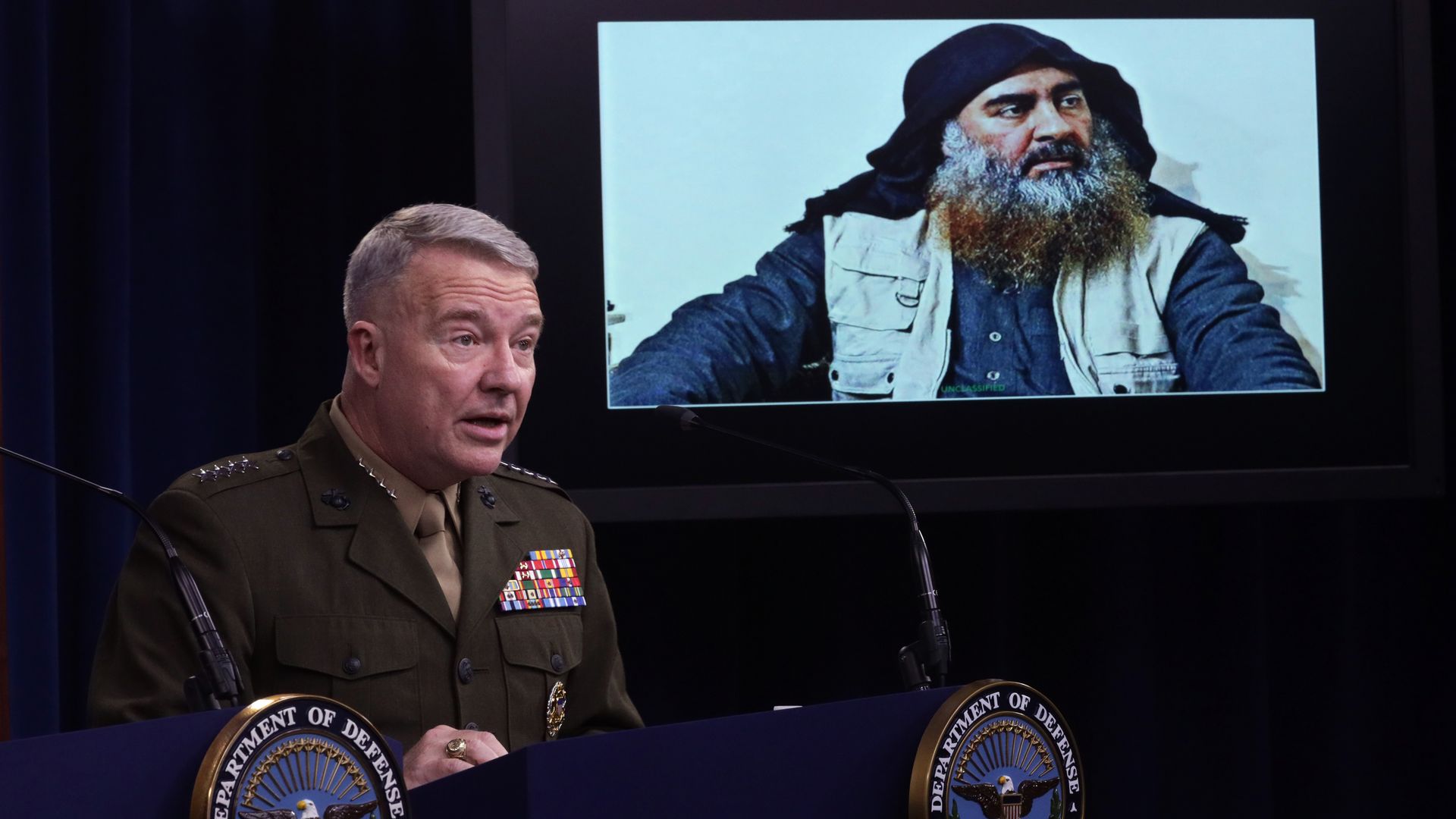 U.S. Marine Corps Gen. Kenneth McKenzie, commander of U.S. Central Command, speaks as a picture of Abu Bakr al-Baghdadi is seen during a press briefing 