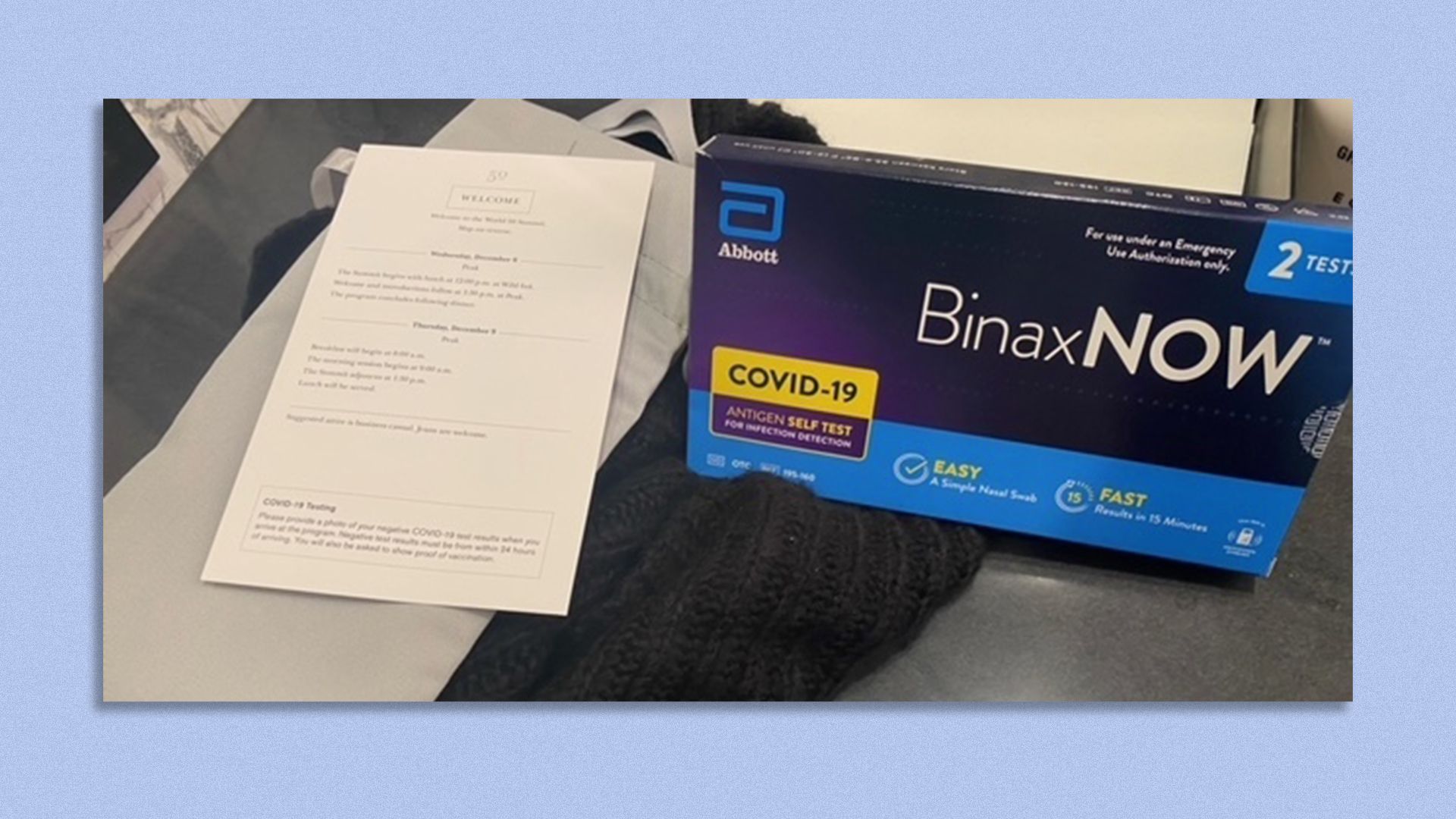 An at-home COVID test next to a business conference agenda.