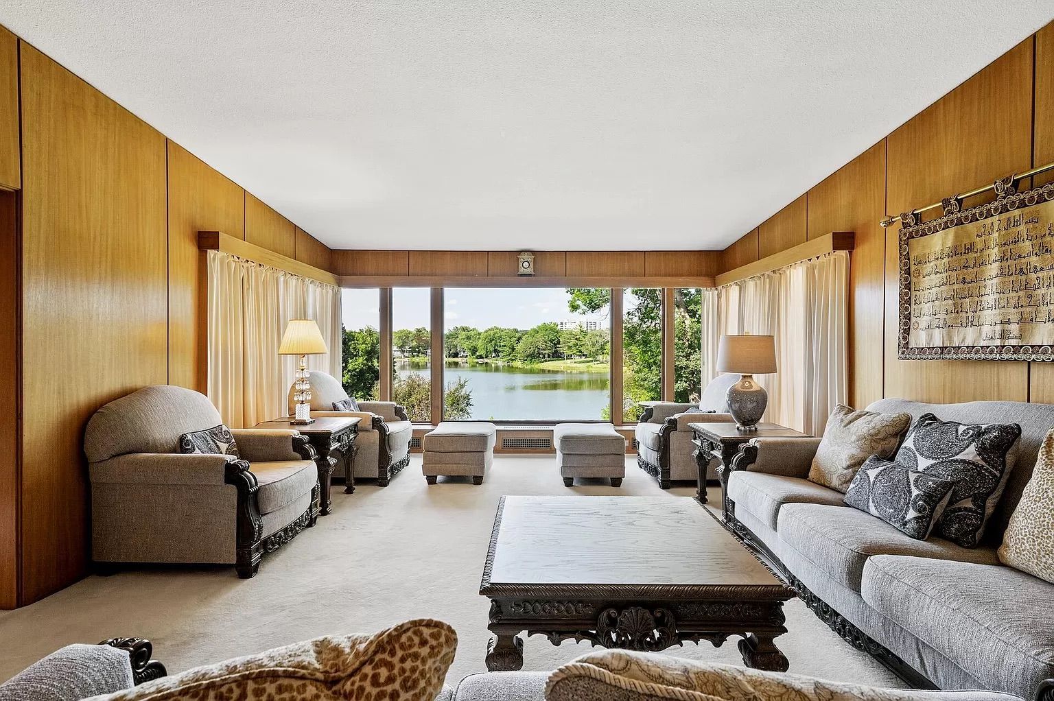 A living room with wood paneled walls and gray furniture.