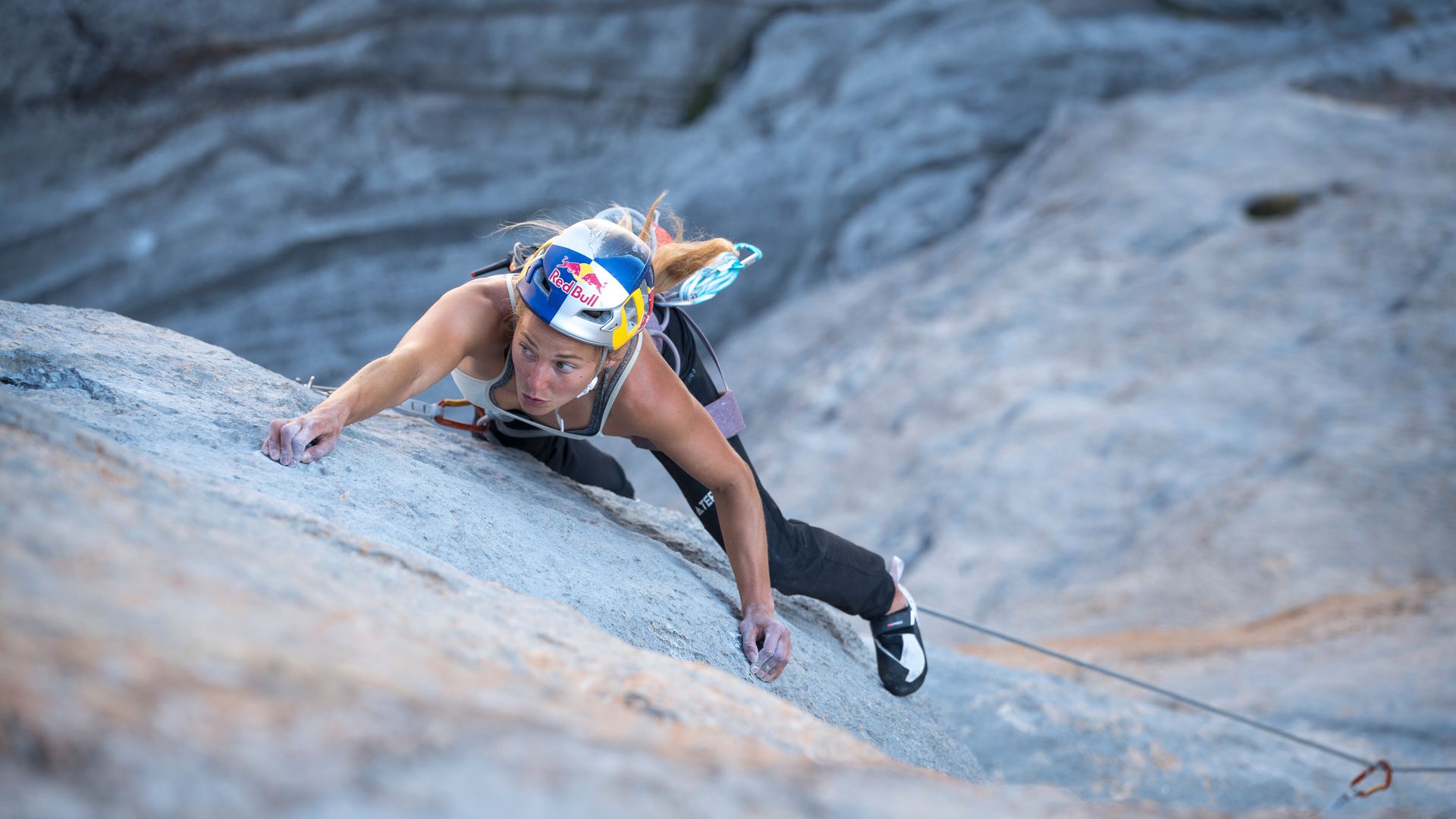 A woman climbs a rock face.