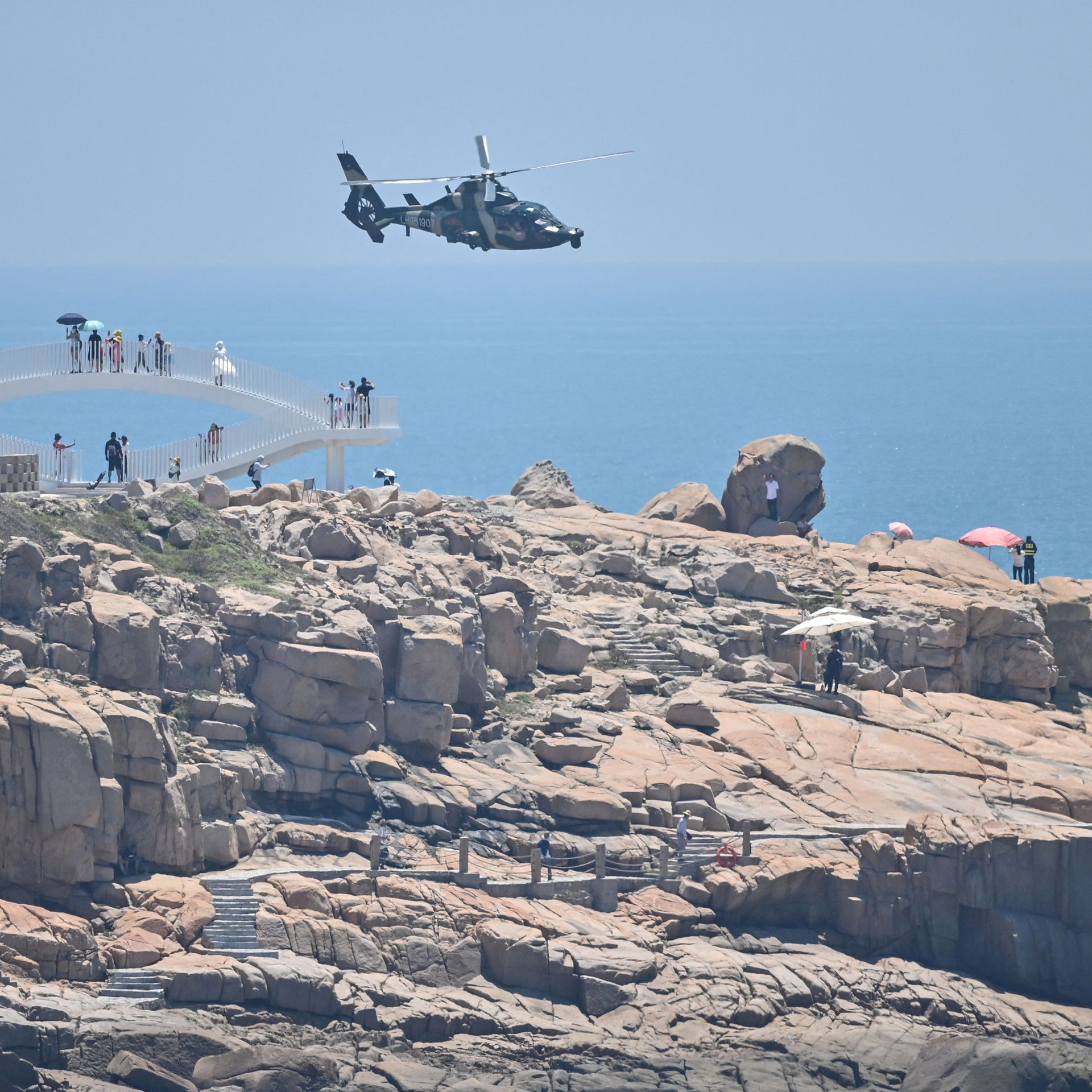 Tourists look on as a Chinese military helicopter flies past Pingtan island, one of mainland China's closest point from Taiwan, in Fujian province on August 4.