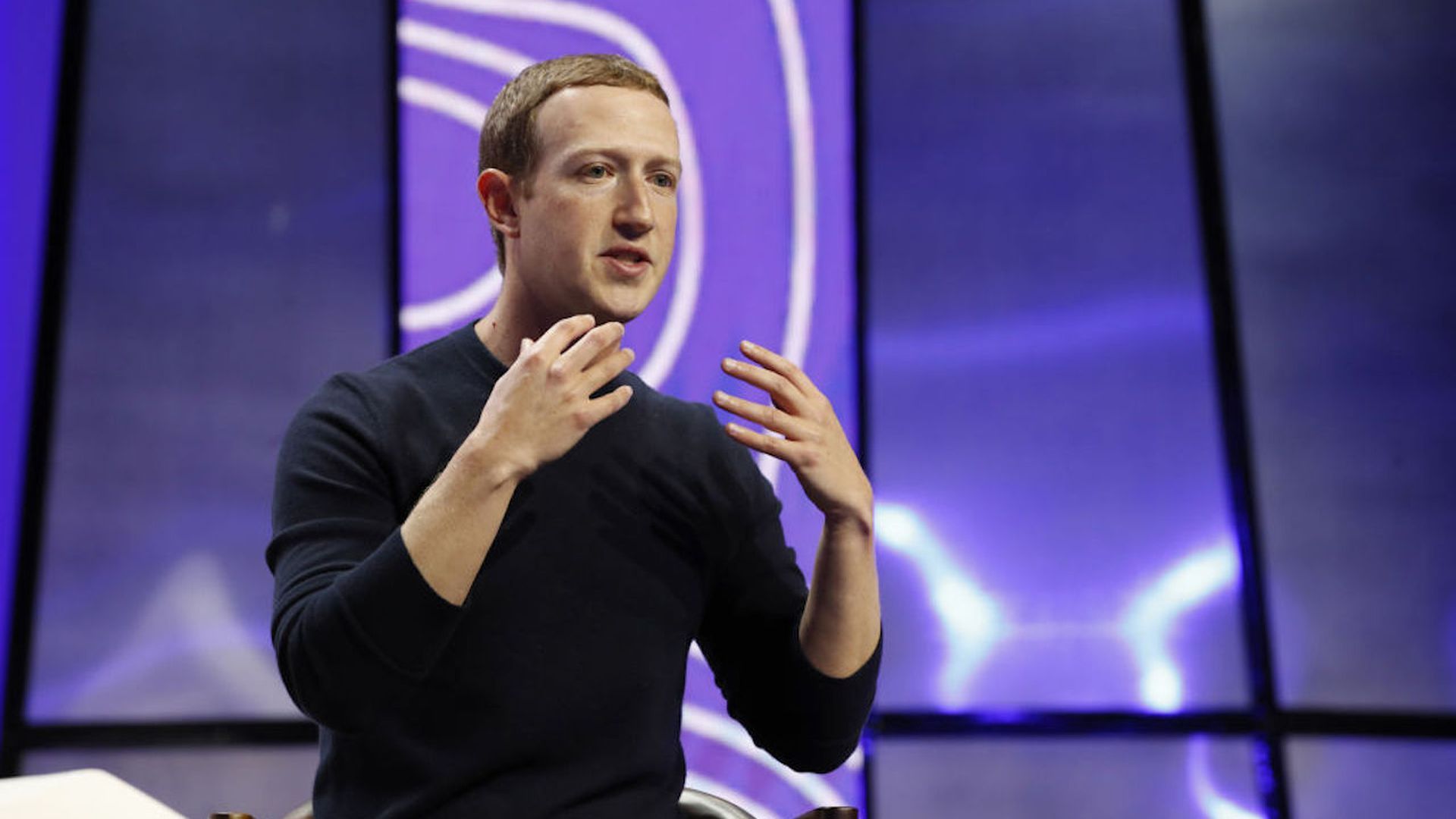 A photo of Meta CEO Mark Zuckerberg speaking on a stage in front of a purple background