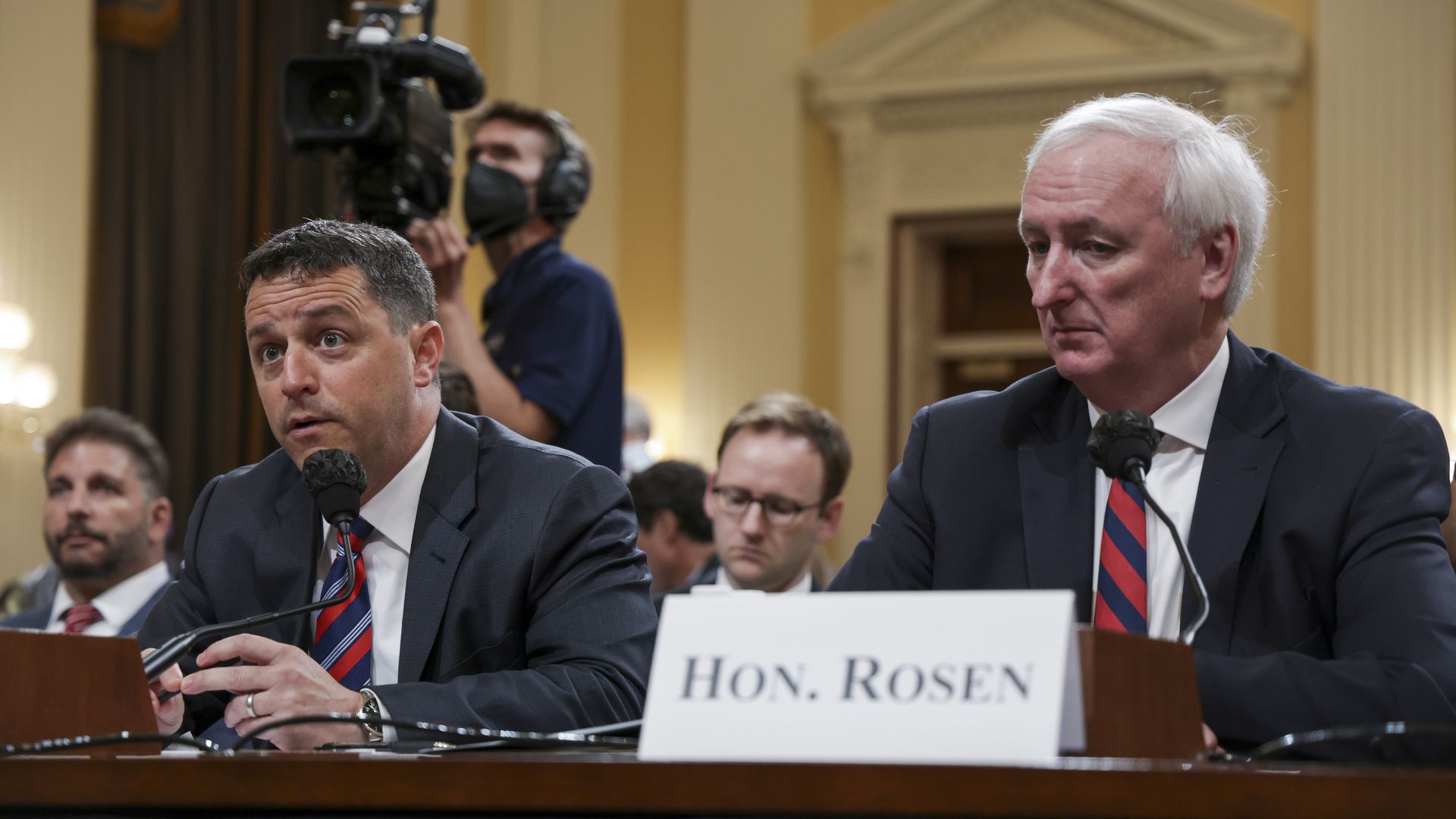 Photo of Steve Engel and Jeff Rosen sitting at a table at a crowded committee hearing