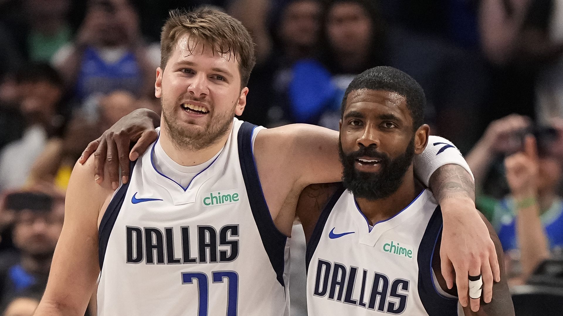 Two men in basketball uniforms with their arms around each other