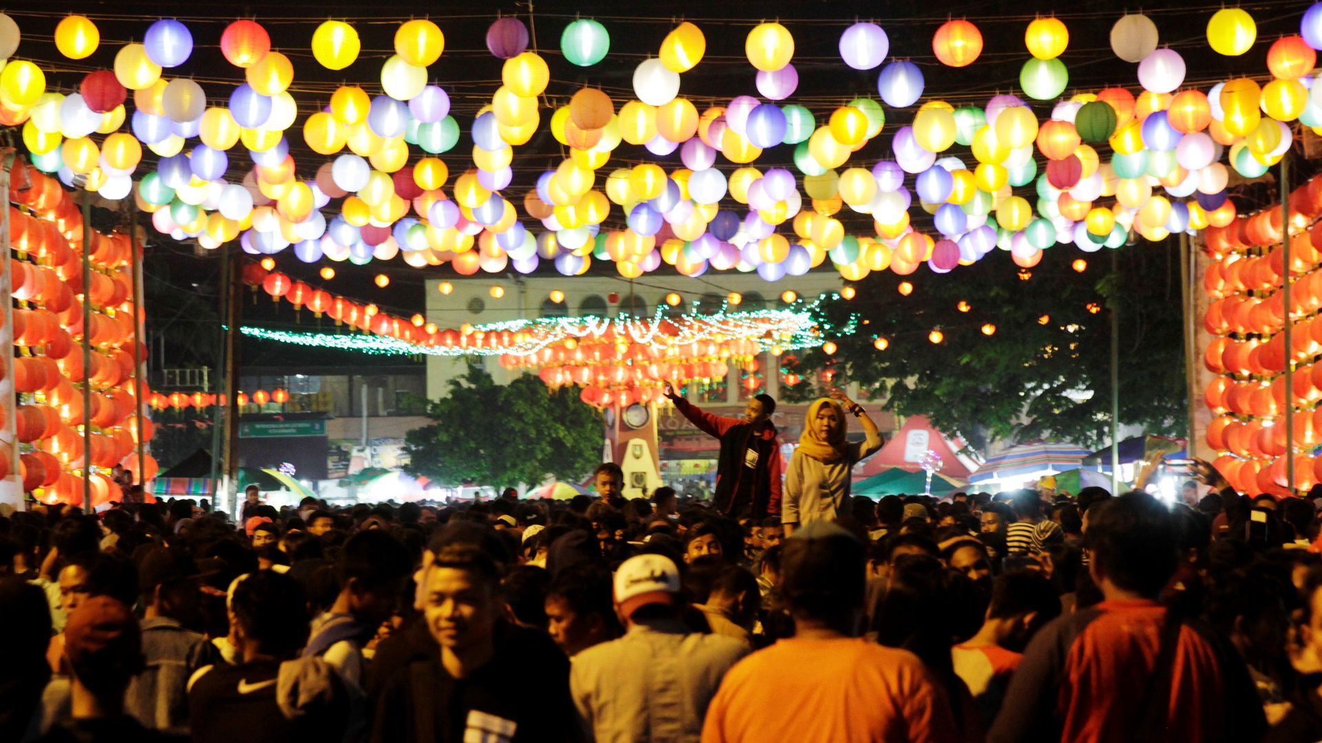 People walking under a canopy of lanterns
