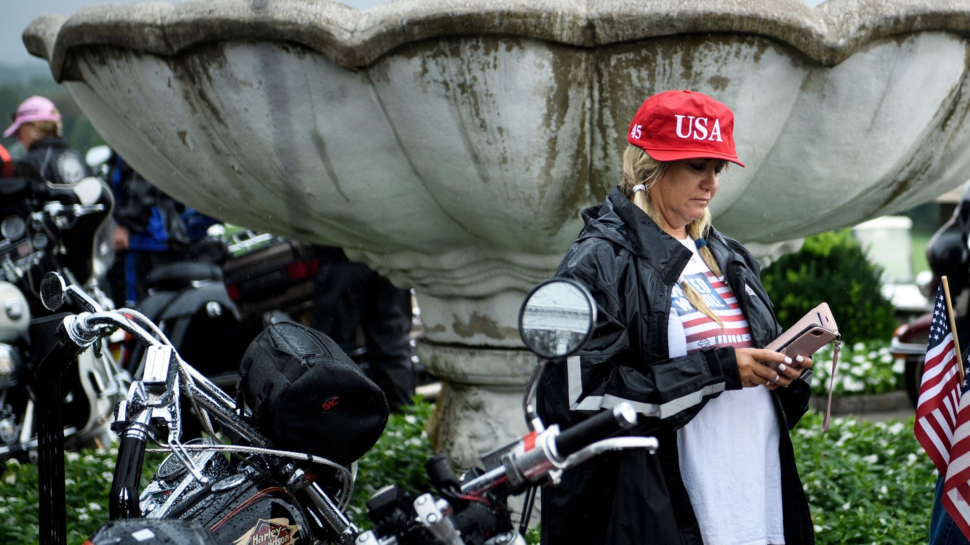 A woman wearing a USA hat looks at her phone.