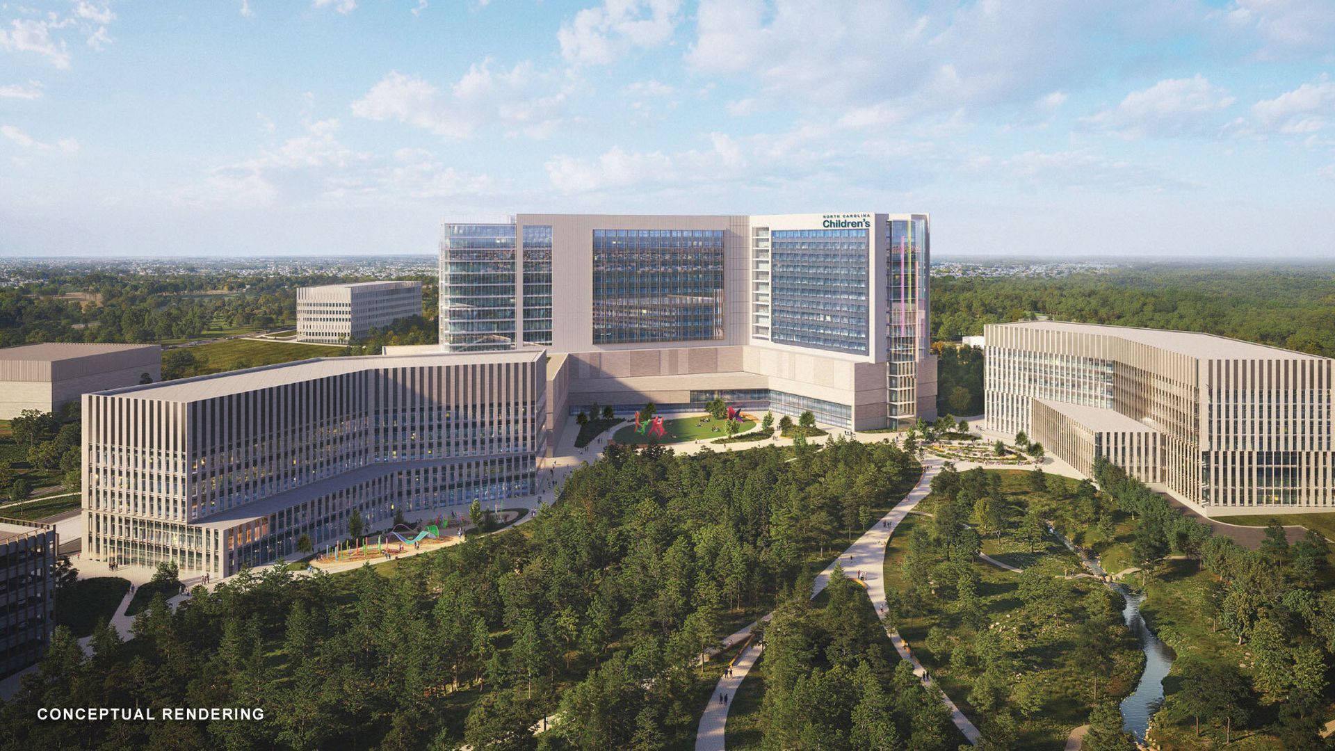 Conceptual rendering of a large medical campus: central glass-front hospital with surrounding wings, a green courtyard and playground, tree-lined grounds, and distant cityscape under a blue sky.