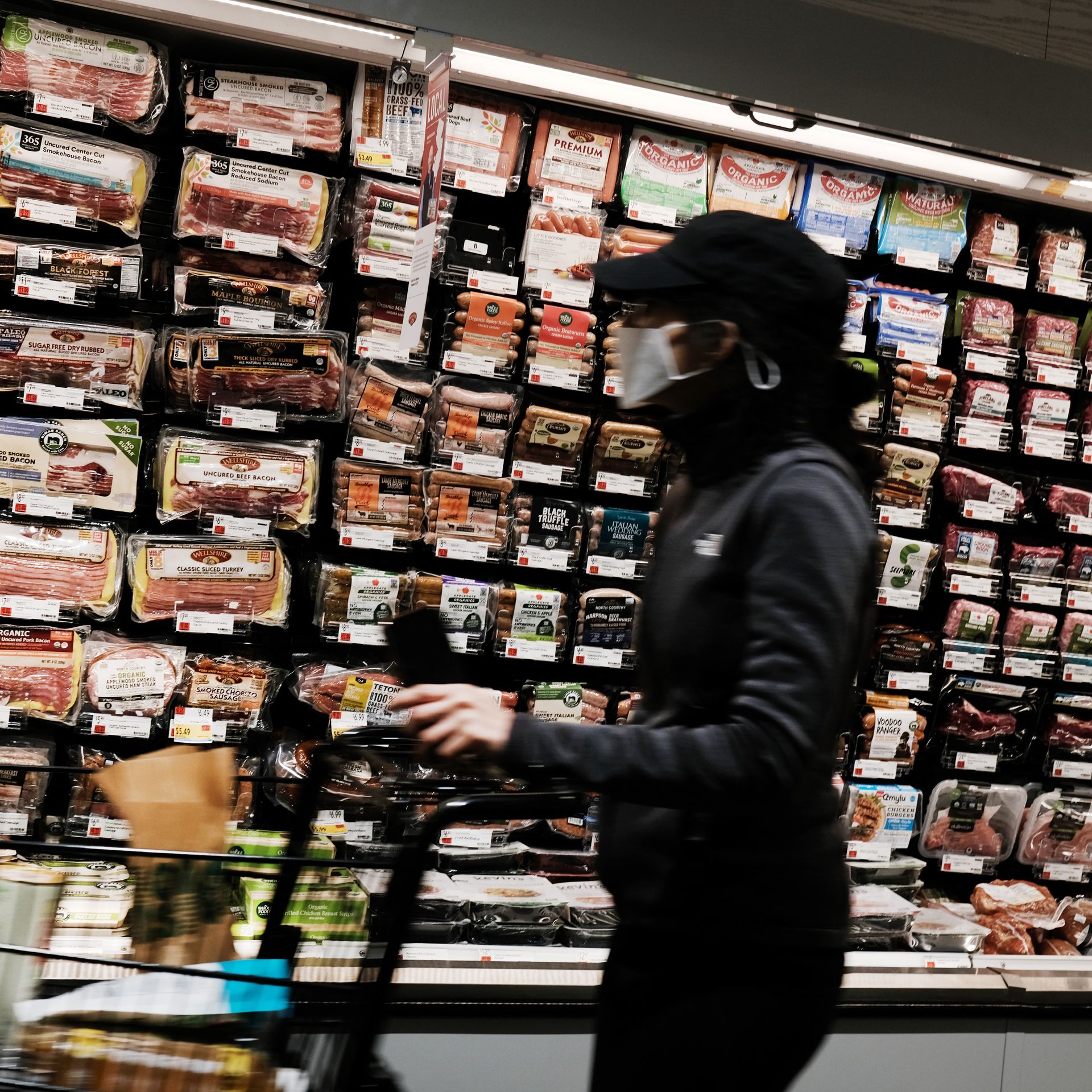 People shopping in the meat aisle in a grocery store 
