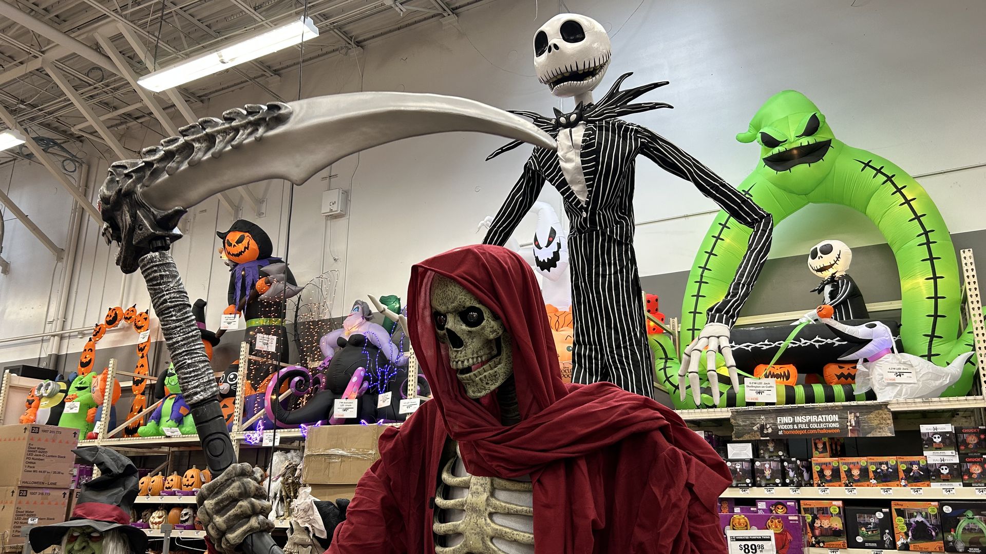 A floor display at Home Depot of Halloween decorations, including a Grim Reaper skeleton and a tall character from nightmare before Christmas