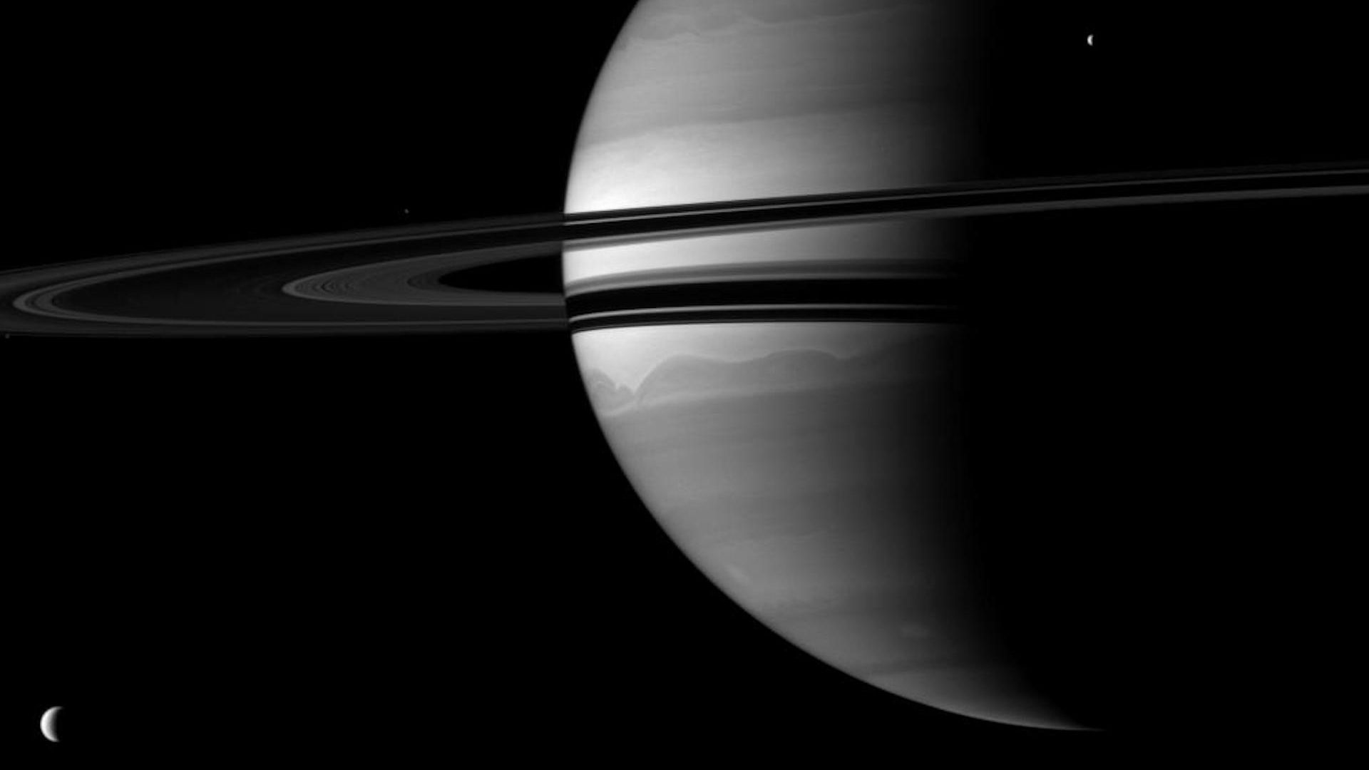 Saturn and two of its moons glow in black and white