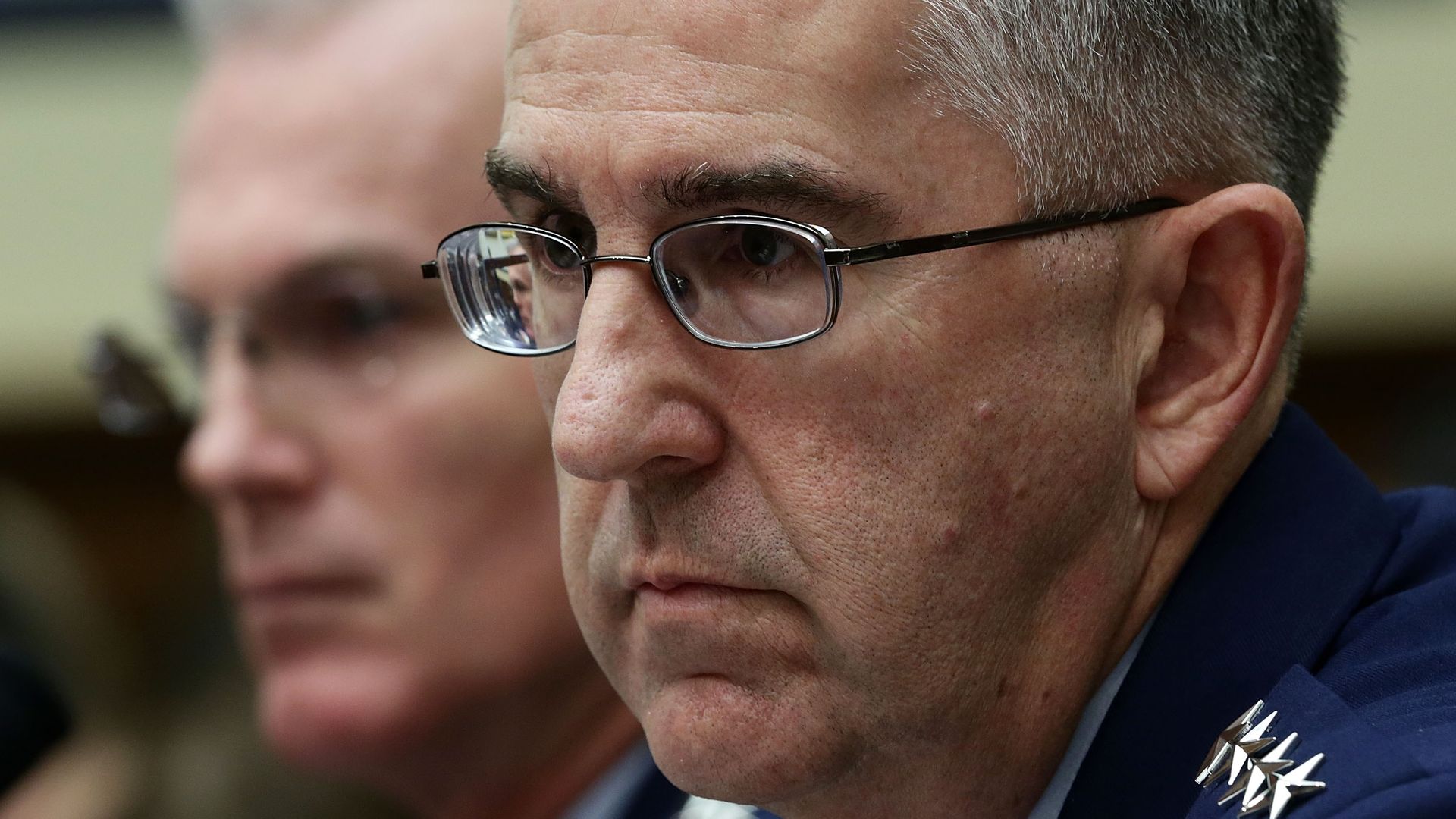 In this image, Hyten sits and listens. He's wearing glasses.