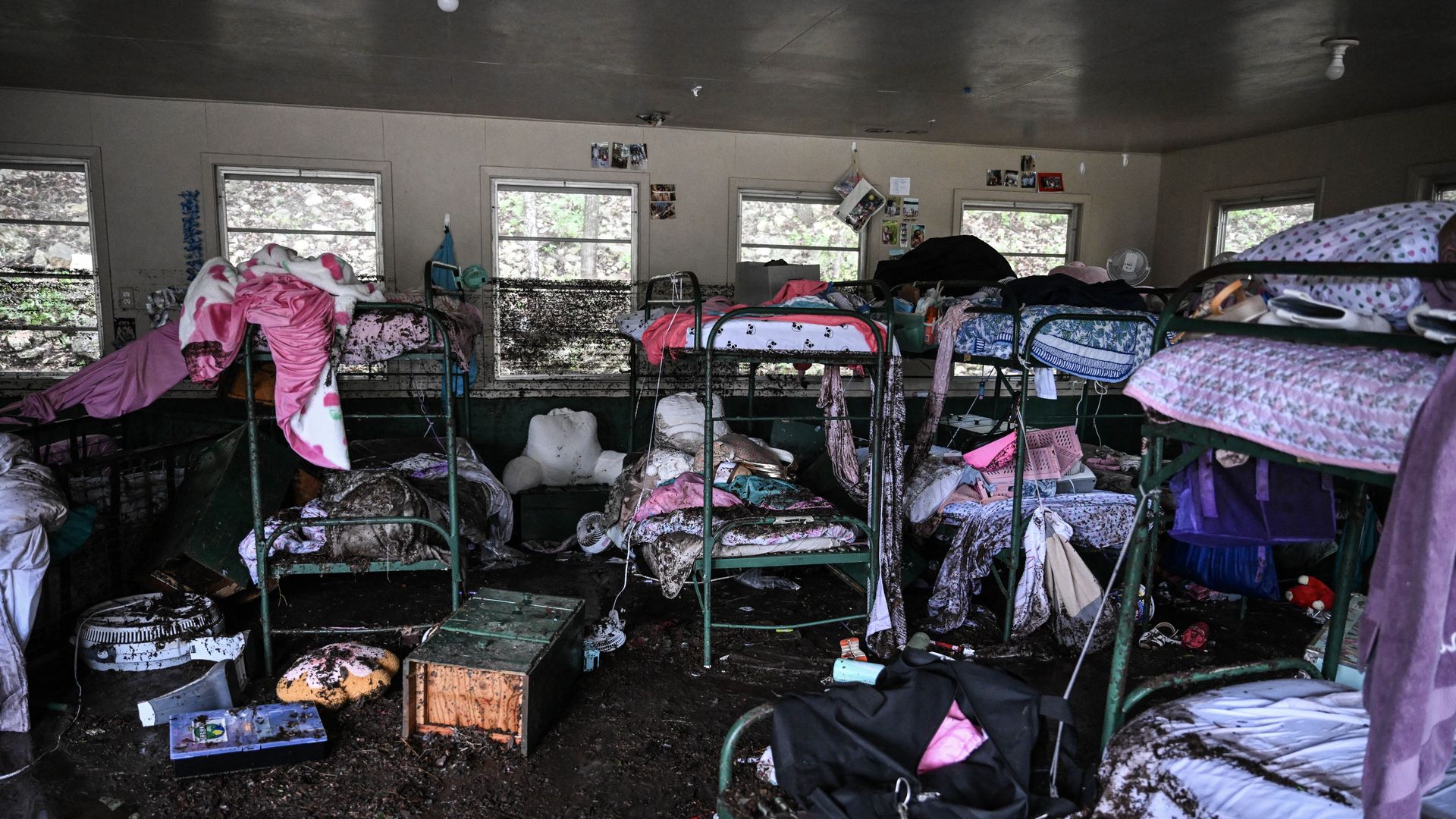 The water-ravaged camp mystic is shwon with multiple bun beds with things strewn across the room